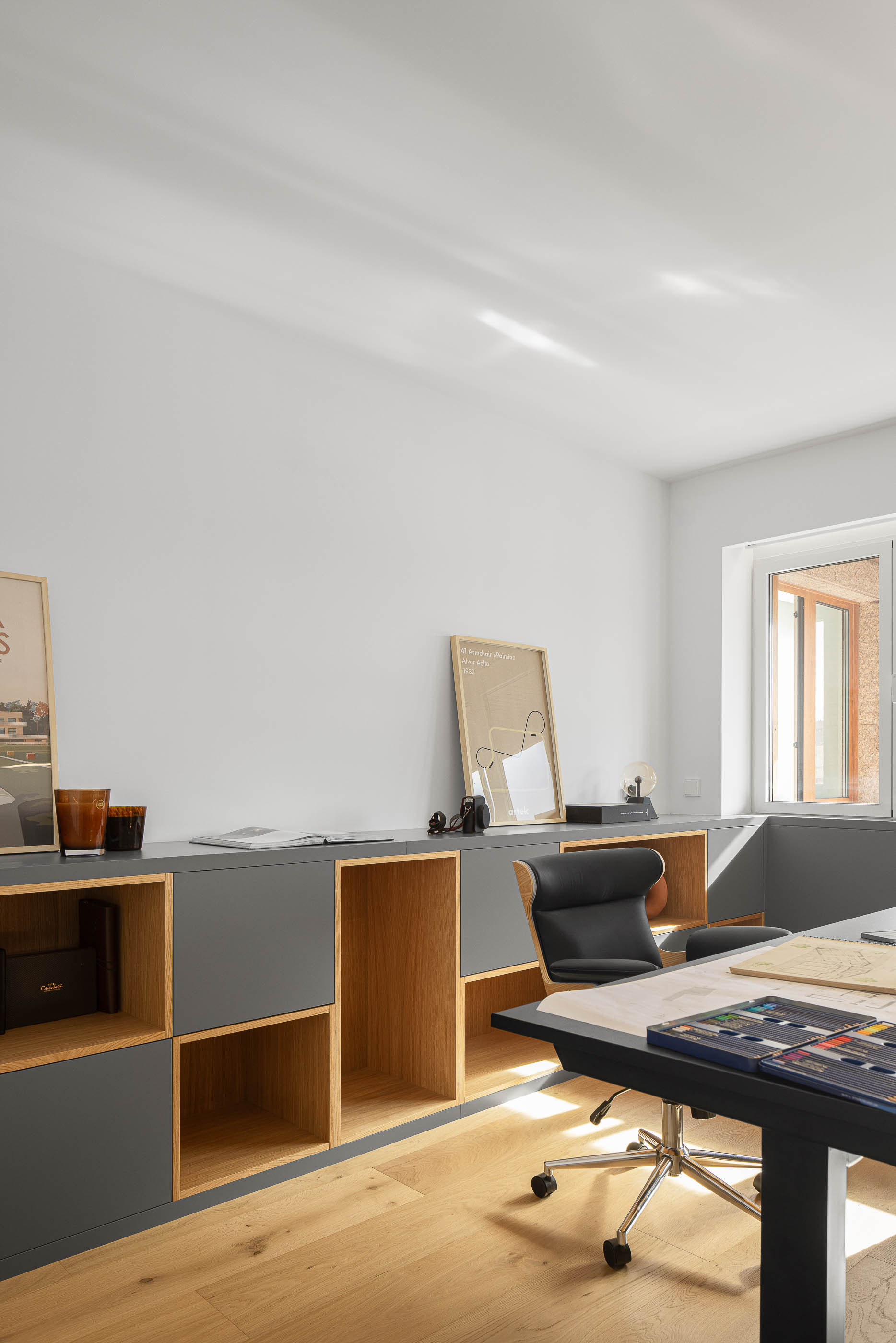 Escritório com secretária preta, cadeira ergonómica e estante com iluminação. Pavimento em madeira clara. — Reforma apartamento CP em Avilés arquitetura David Olmos Arquitectos em Avilés