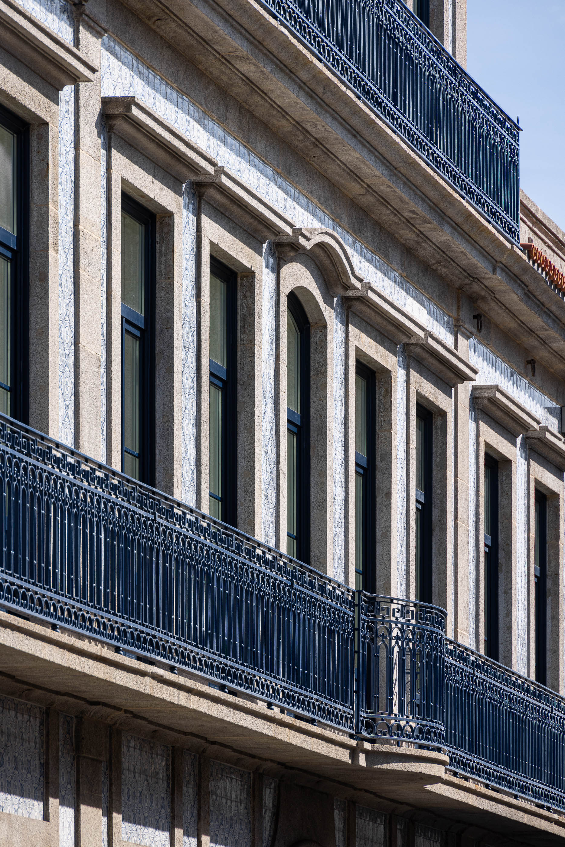 Fachada: Edifício clássico com varandas em ferro forjado, janelas escuras e revestimento em azulejo padrão. — Condomínio das Artes arquitetura MiMool Arquitectura & Interiores em Porto