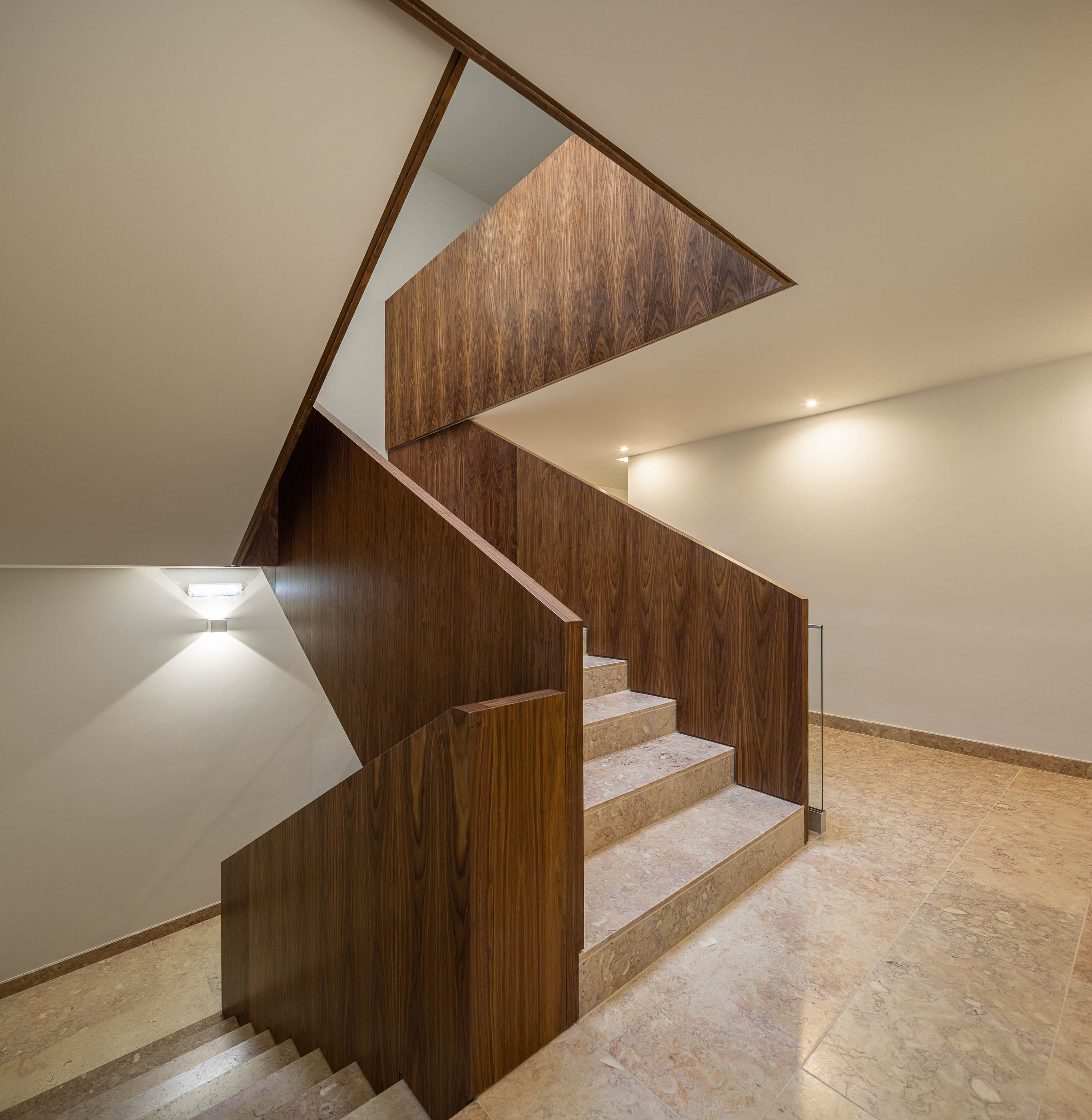 Escadas: Detalhe do corrimão em madeira escura e degraus em mármore claro. — Condomínio das Artes arquitetura MiMool Arquitectura & Interiores em Porto