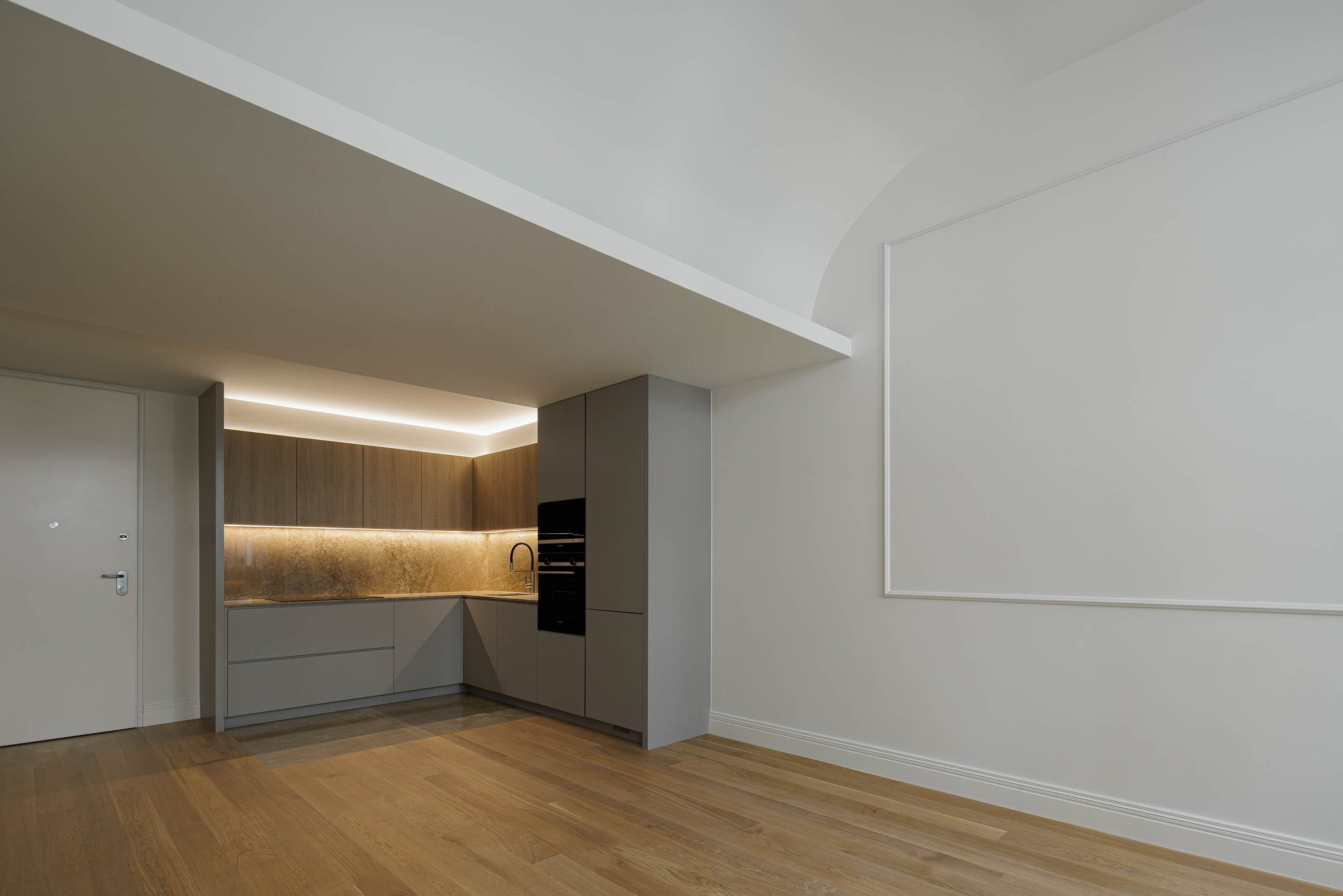 Cozinha: Armários cinzentos e em madeira, bancada em pedra e pavimento em madeira clara. — Condomínio das Artes arquitetura MiMool Arquitectura & Interiores em Porto