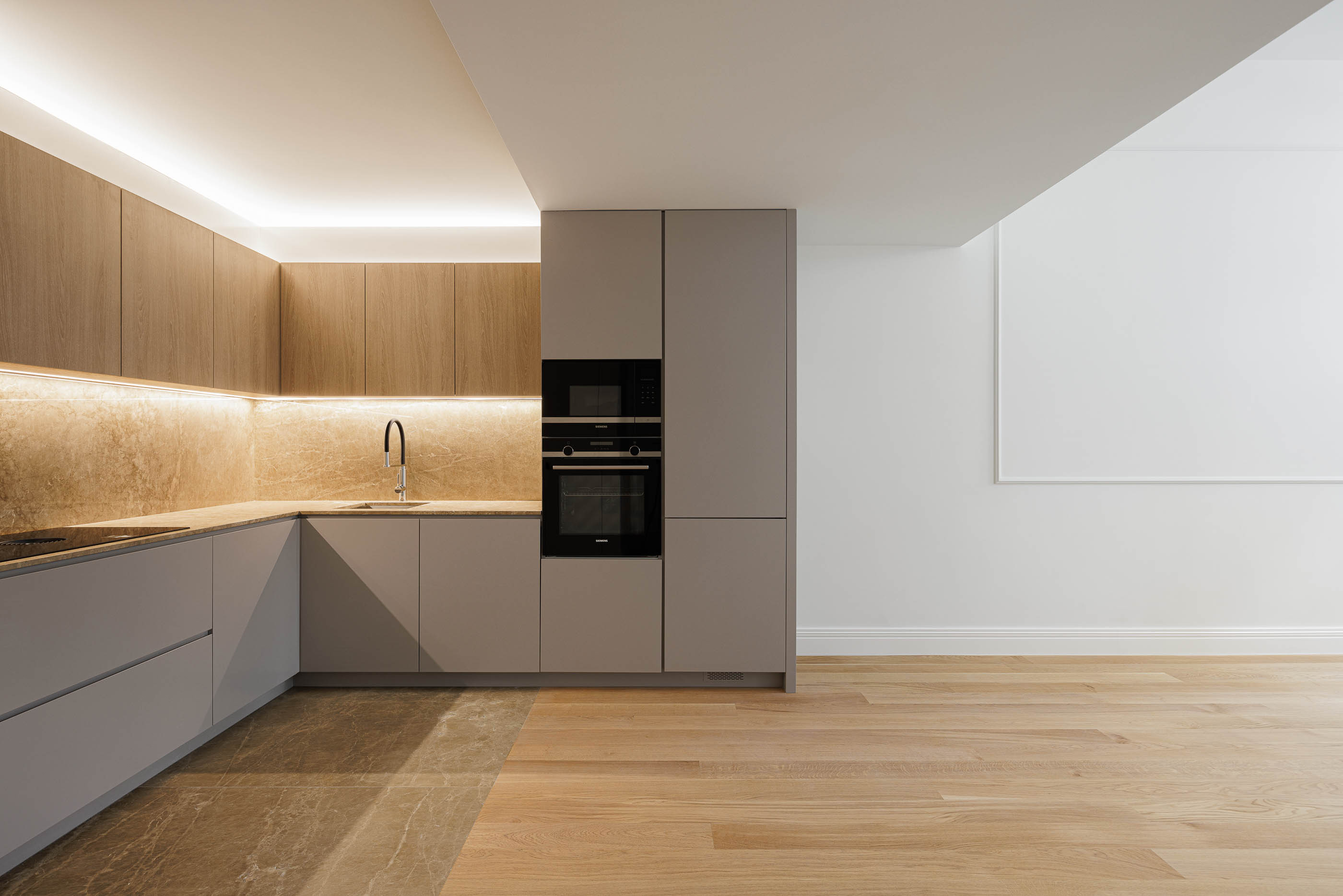 Cozinha: Armários cinzentos e em madeira, eletrodomésticos pretos e pavimento em madeira clara. — Condomínio das Artes arquitetura MiMool Arquitectura & Interiores em Porto
