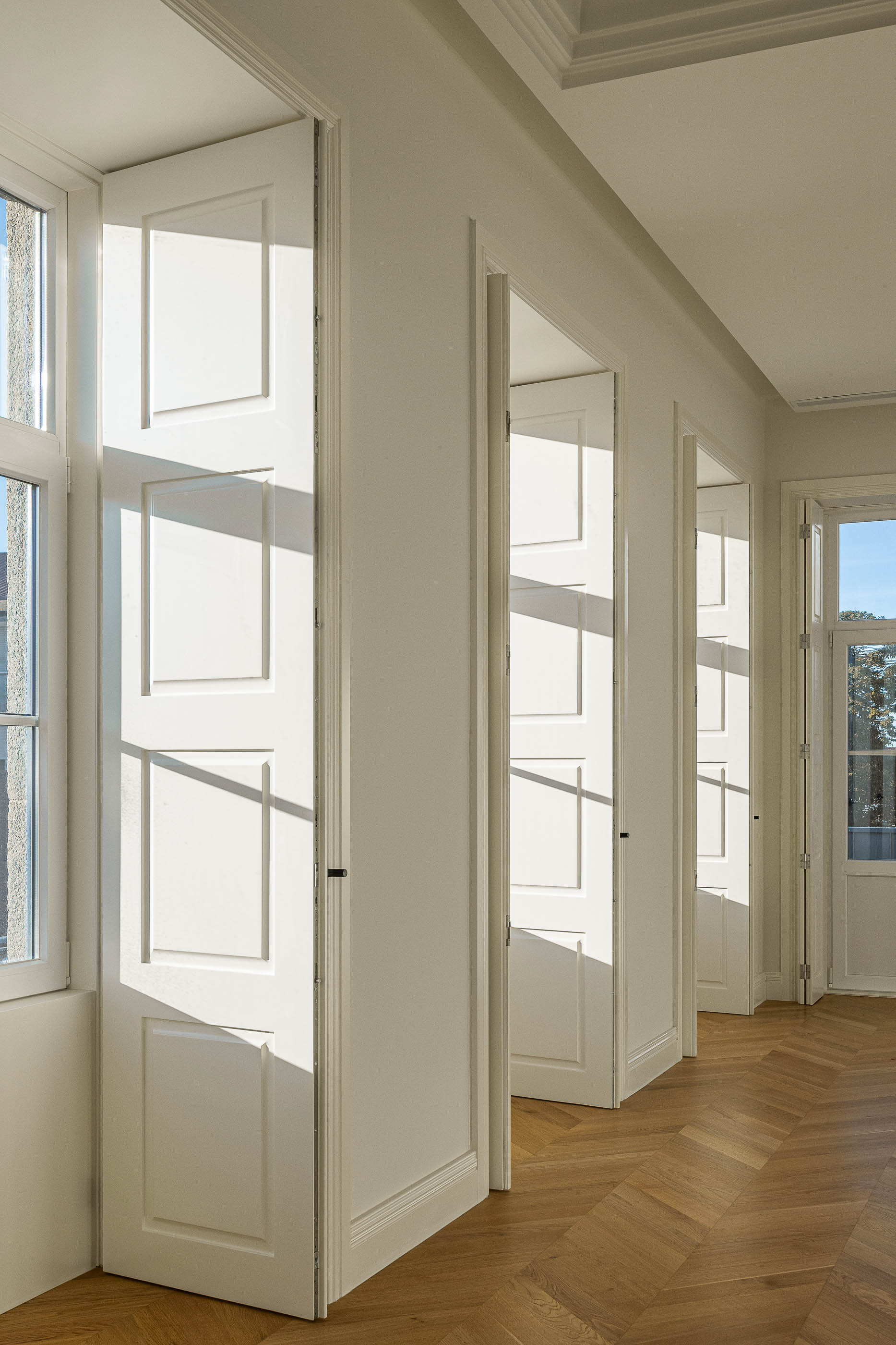 Sala de estar: Janelas com portadas brancas e pavimento em madeira espinha de peixe. — Condomínio das Artes arquitetura MiMool Arquitectura & Interiores em Porto