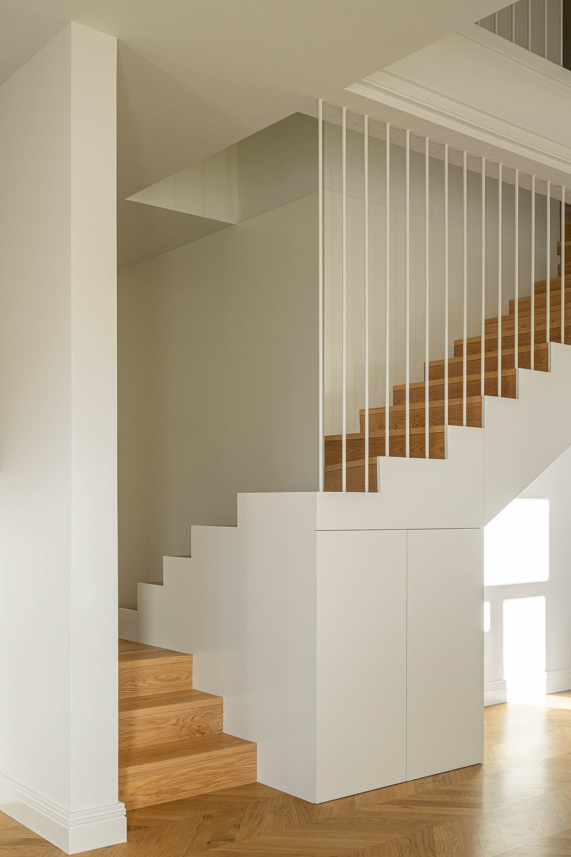 Escadas: Escadas em madeira clara com corrimão branco e pavimento em madeira espinha de peixe. — Condomínio das Artes arquitetura MiMool Arquitectura & Interiores em Porto