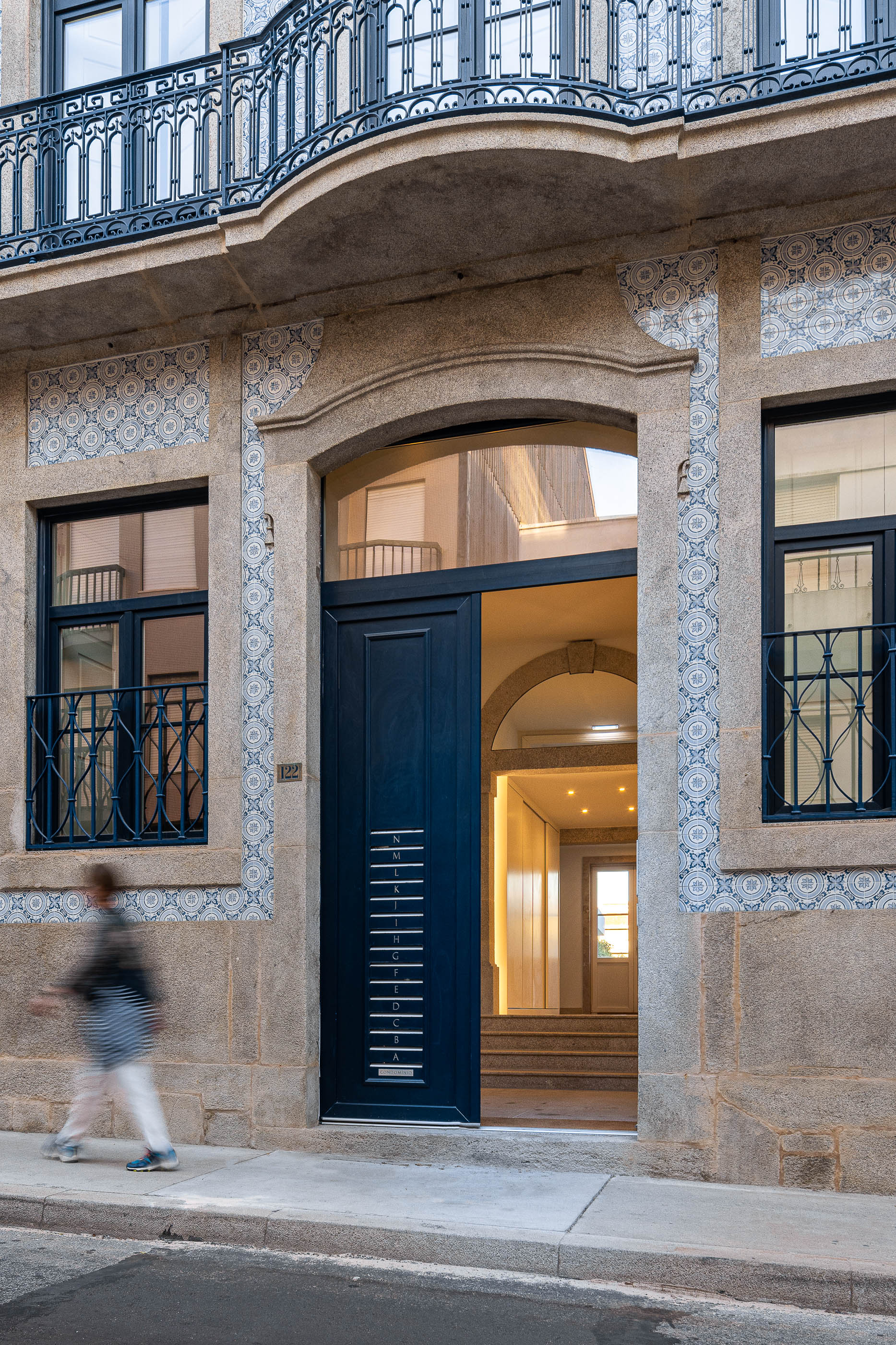 Fachada: Porta de entrada azul, azulejos decorativos e detalhes em pedra. — Condomínio das Artes arquitetura MiMool Arquitectura & Interiores em Porto