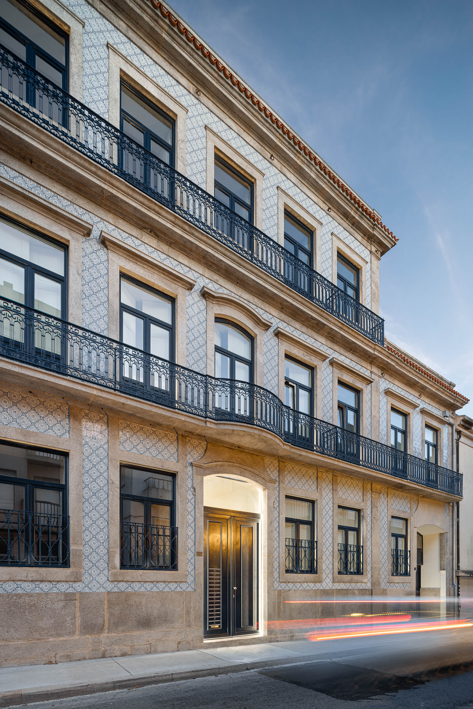Fachada: Edifício clássico com varandas em ferro forjado e revestimento em azulejo padrão. — Condomínio das Artes arquitetura MiMool Arquitectura & Interiores em Porto