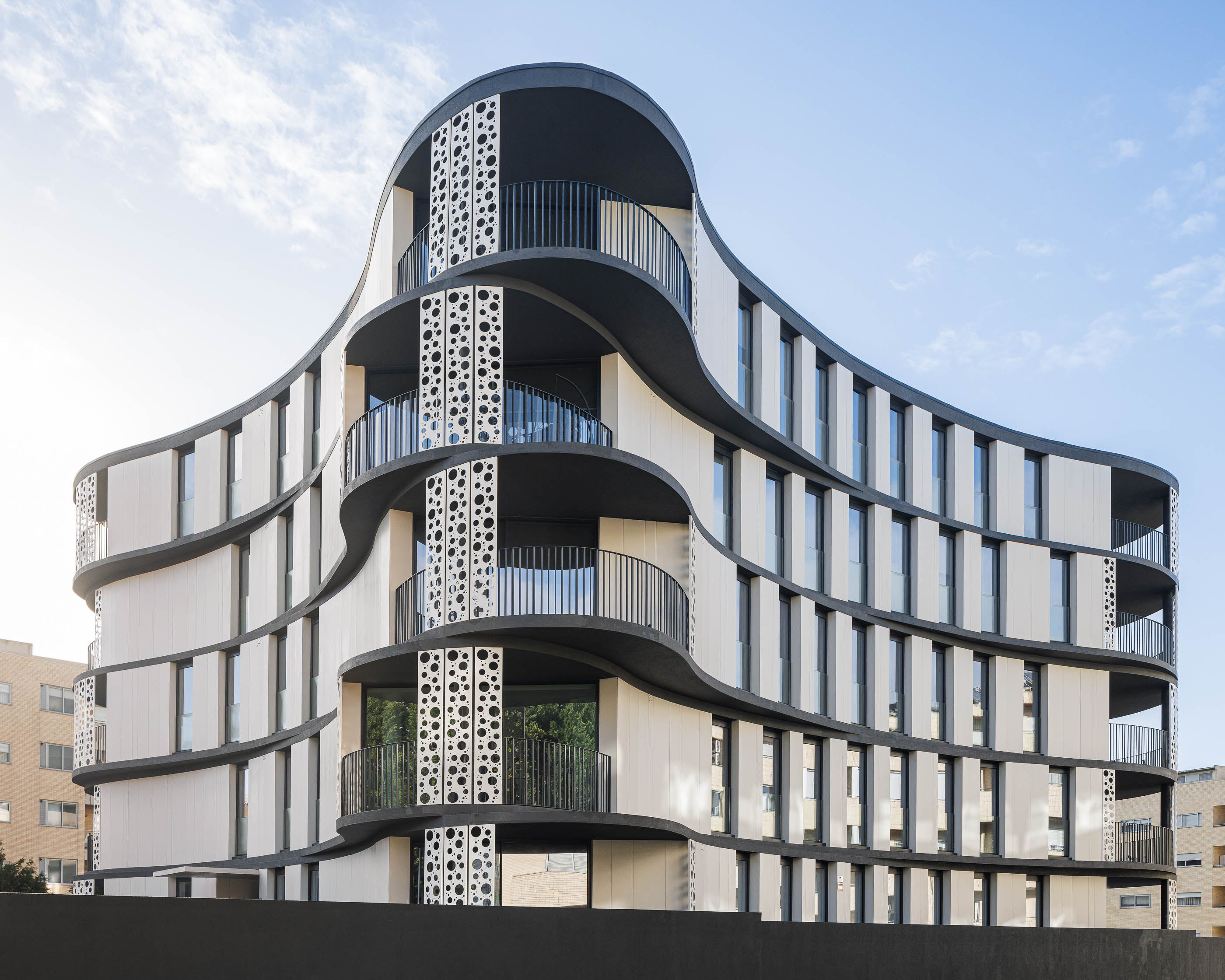 Fachada: Edifício moderno com varandas curvas, painéis brancos e cinzentos, e elementos decorativos circulares. — Edifício Sense 100 arquitetura Sandra Micaela Casinha Atelier em Rio Tinto