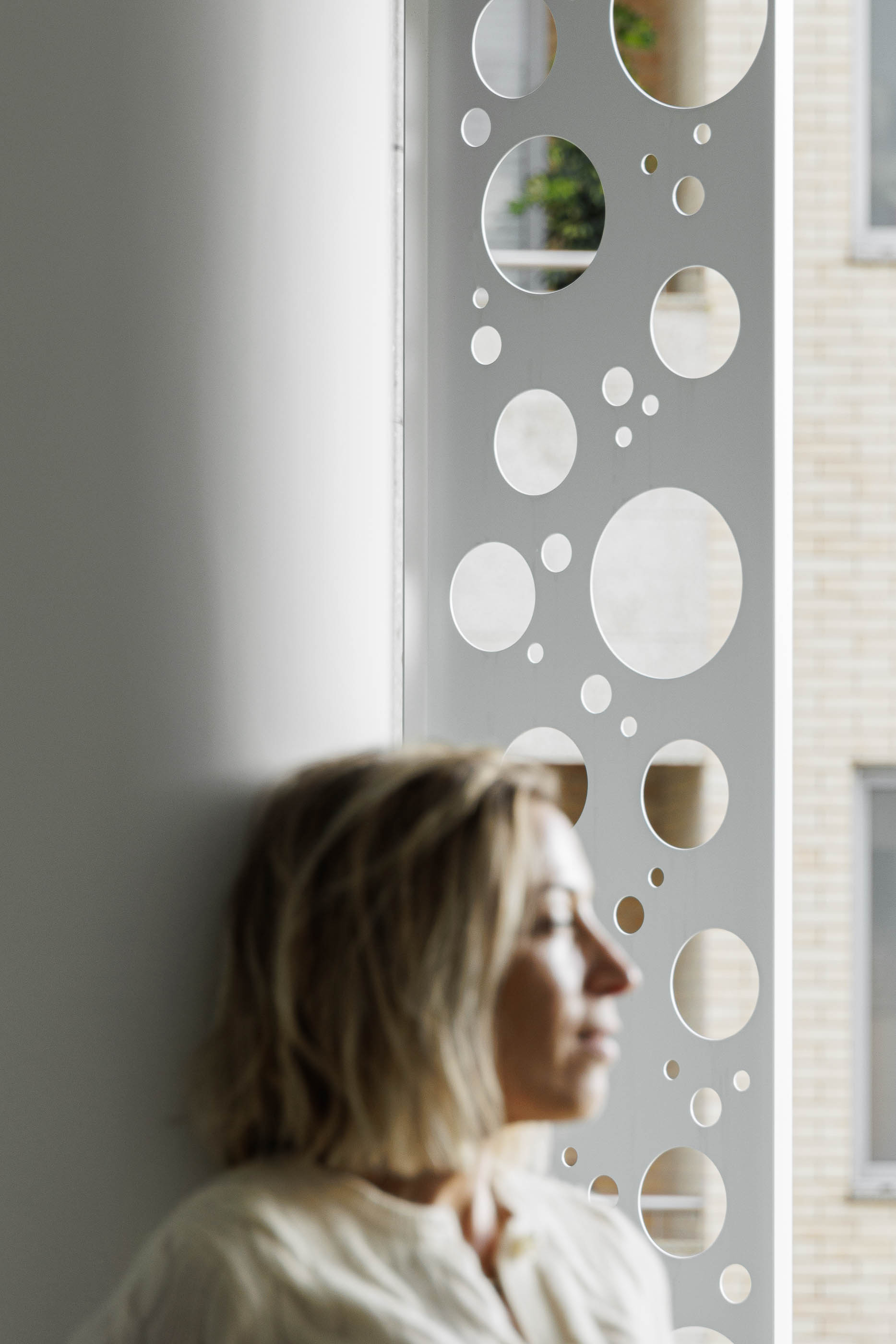 Varanda: Detalhe da estrutura com perfurações circulares e vista para o exterior. — Edifício Sense 100 arquitetura Sandra Micaela Casinha Atelier em Rio Tinto