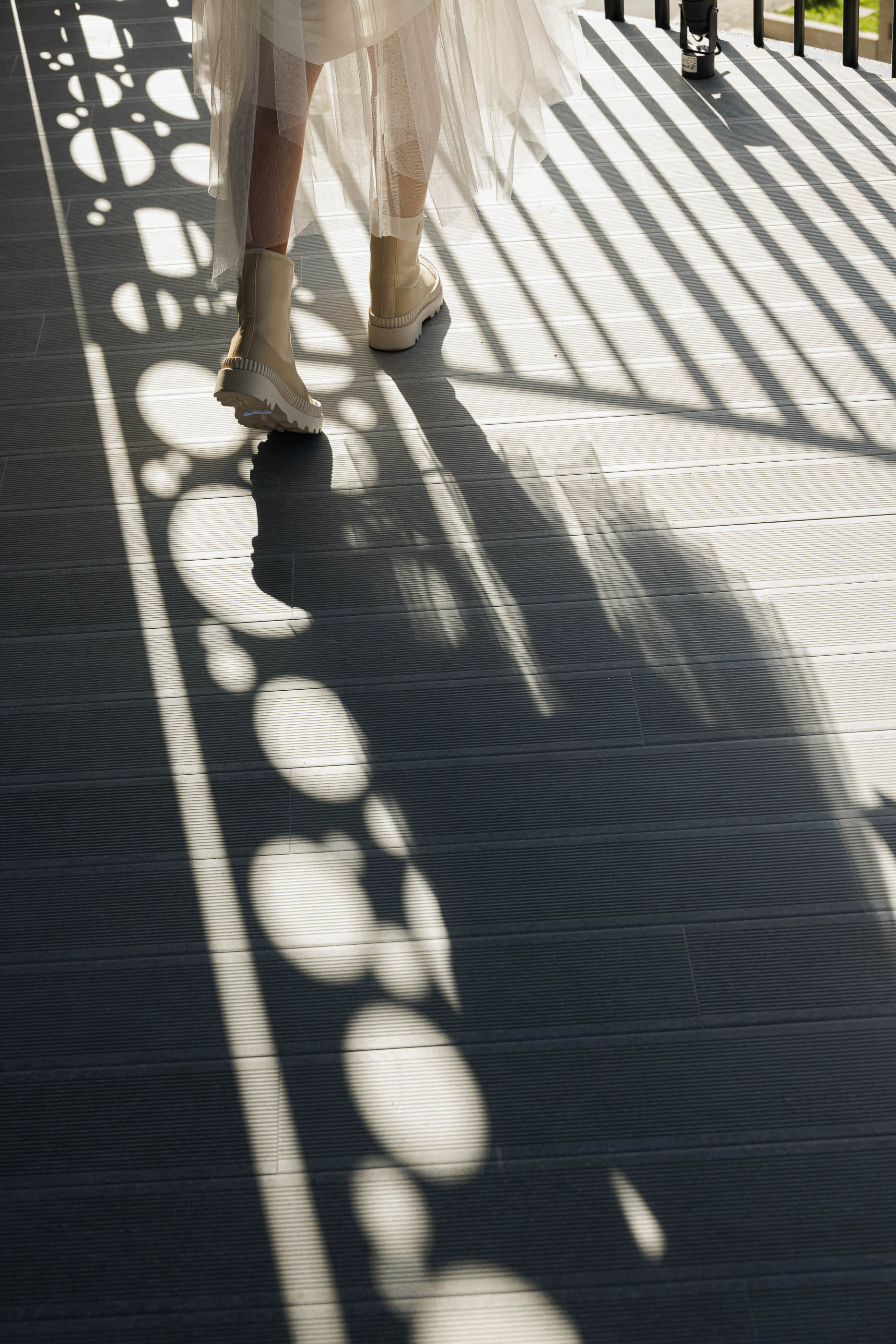 Varanda: Detalhe do pavimento em madeira da varanda, com sombras criadas pela estrutura perfurada. — Edifício Sense 100 arquitetura Sandra Micaela Casinha Atelier em Rio Tinto