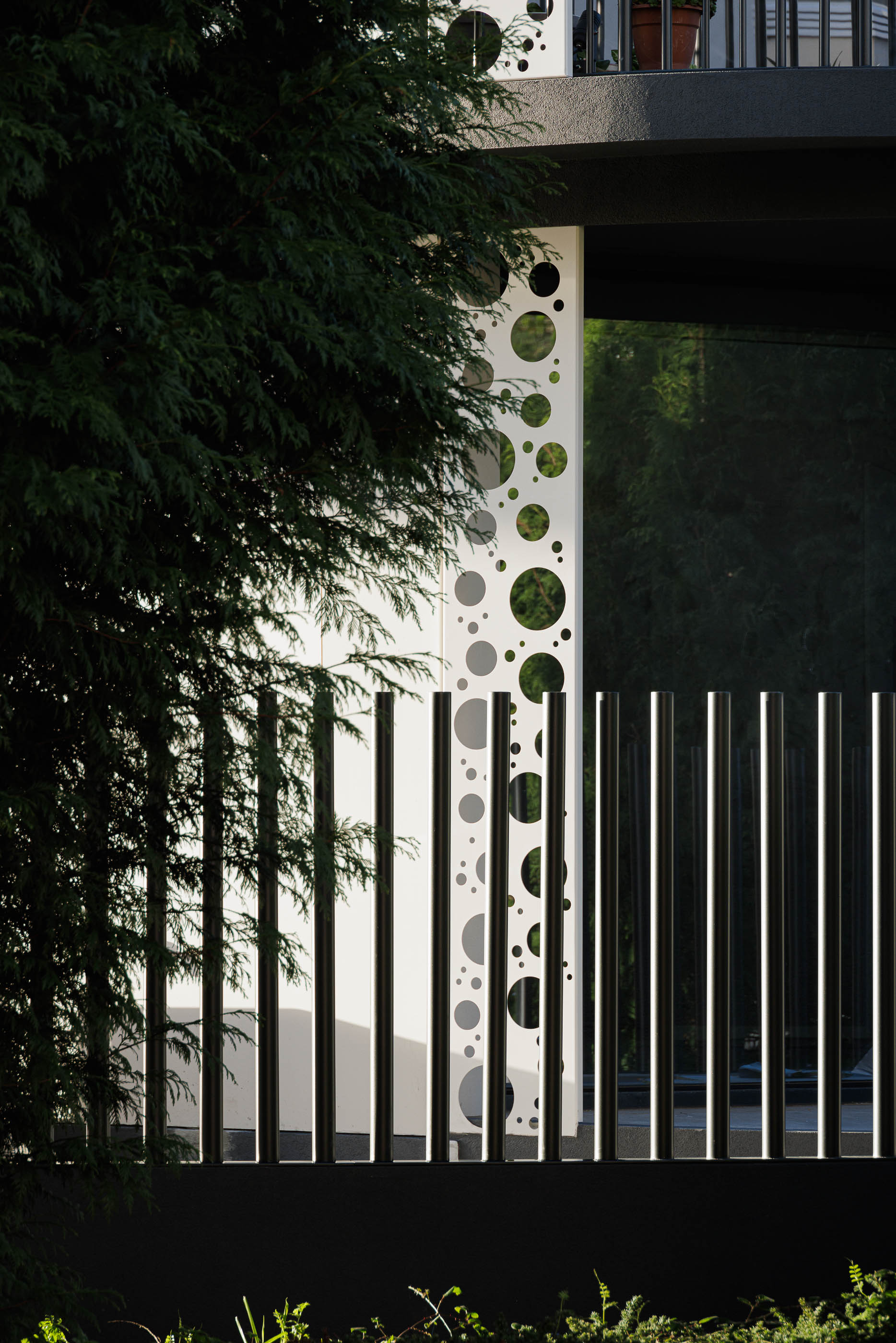 Exterior: Detalhe da fachada com painéis brancos e cinzentos, e vegetação em primeiro plano. — Edifício Sense 100 arquitetura Sandra Micaela Casinha Atelier em Rio Tinto