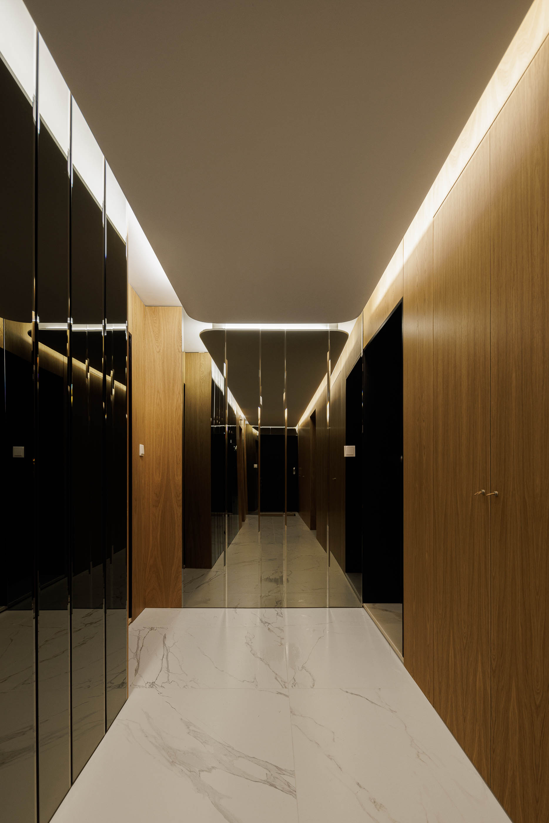 Corredor: Espaço com paredes em madeira, espelhos e pavimento em mármore branco, com iluminação embutida. — Edifício Sense 100 arquitetura Sandra Micaela Casinha Atelier em Rio Tinto
