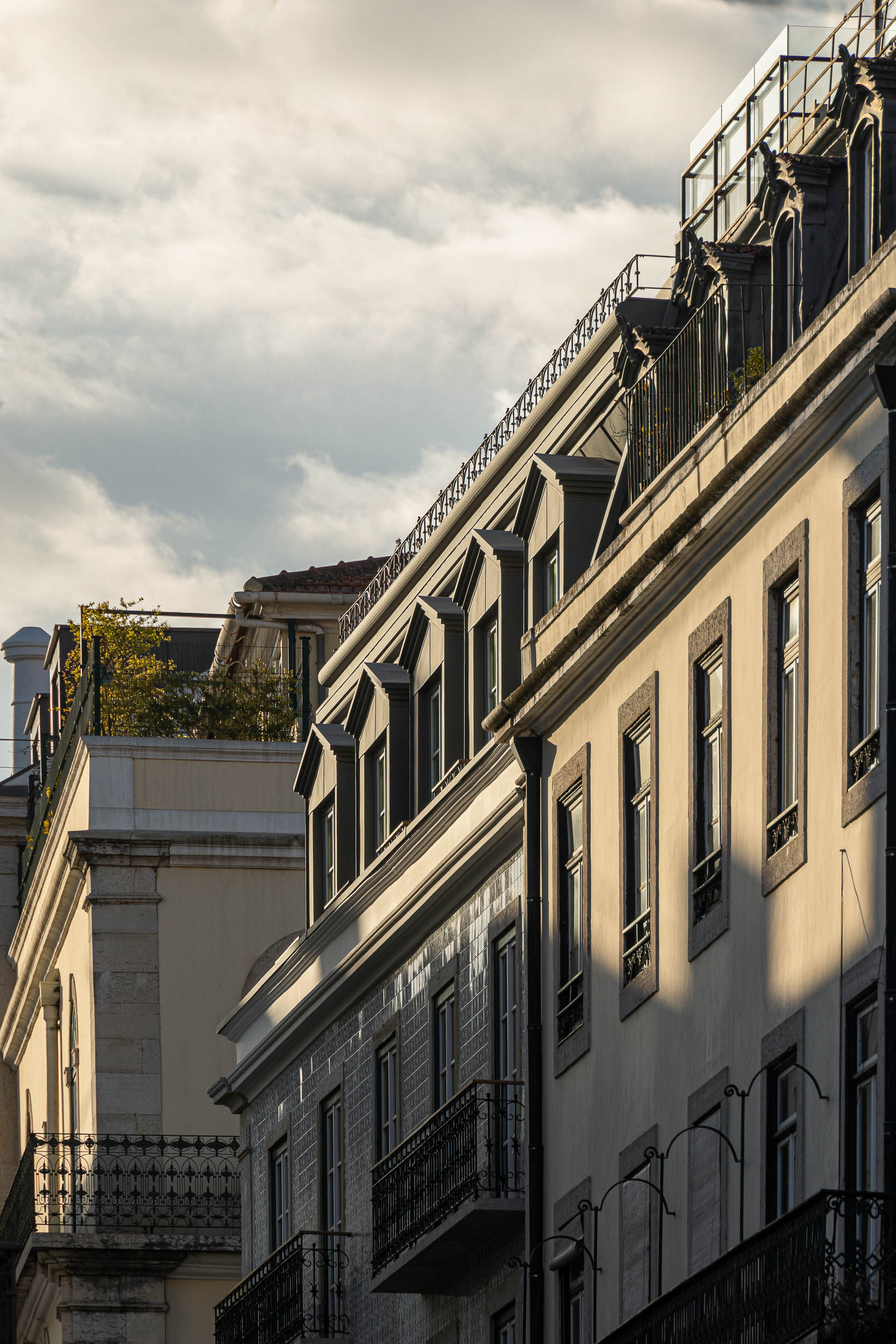 Fachada: Edifício histórico com janelas emolduradas e mansardas, sob um céu nublado. — Victor Cordon arquitetura Fragmentos em Lisboa