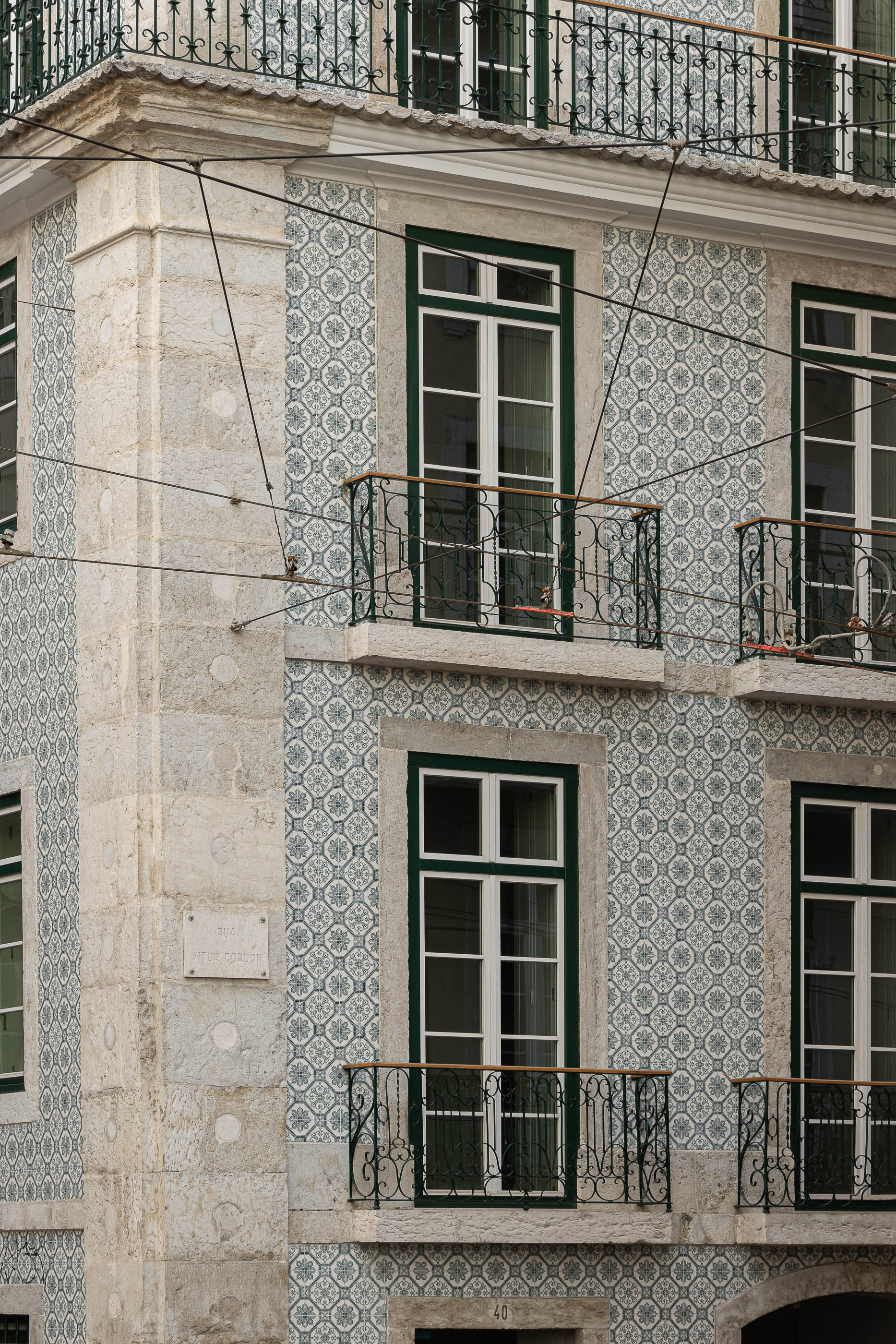 Fachada: Detalhe da fachada de um edifício com azulejos decorativos e varandas em ferro forjado. — Victor Cordon arquitetura Fragmentos em Lisboa