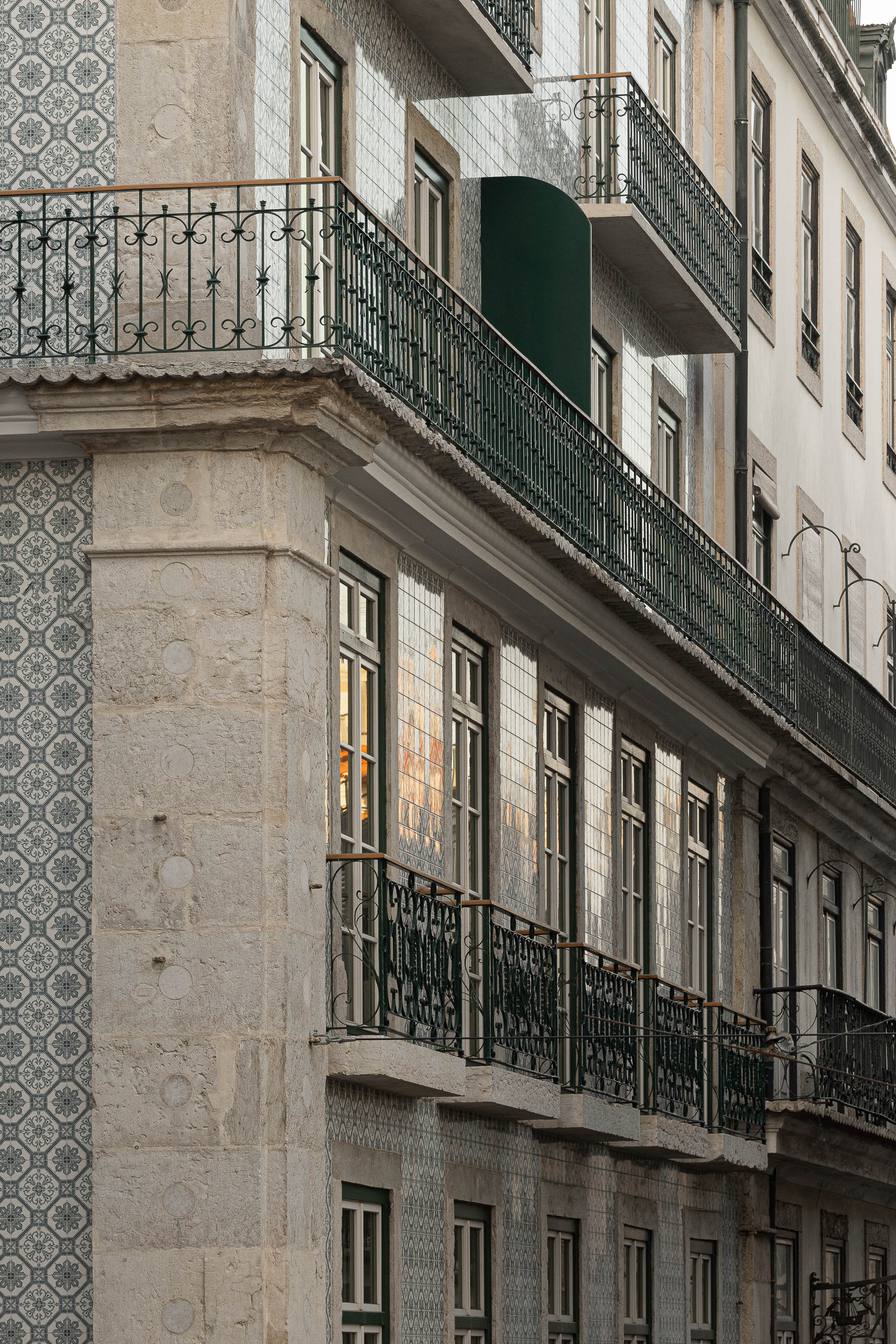 Fachada: Vista angular de um edifício com varandas em ferro e fachada revestida a azulejos tradicionais. — Victor Cordon arquitetura Fragmentos em Lisboa