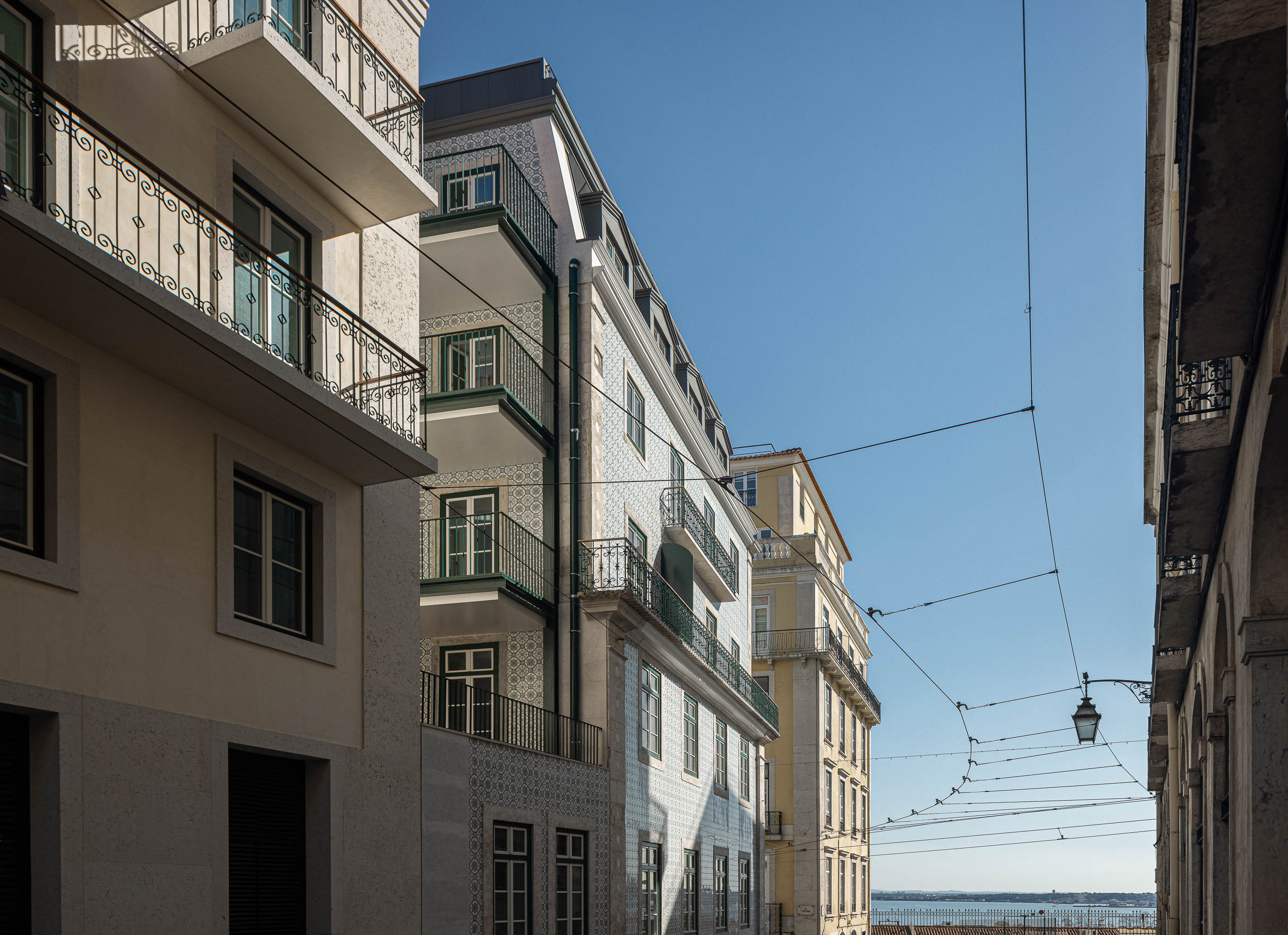 Rua: Perspectiva de edifícios históricos com varandas, sob um céu azul, numa rua de Lisboa. — Victor Cordon arquitetura Fragmentos em Lisboa