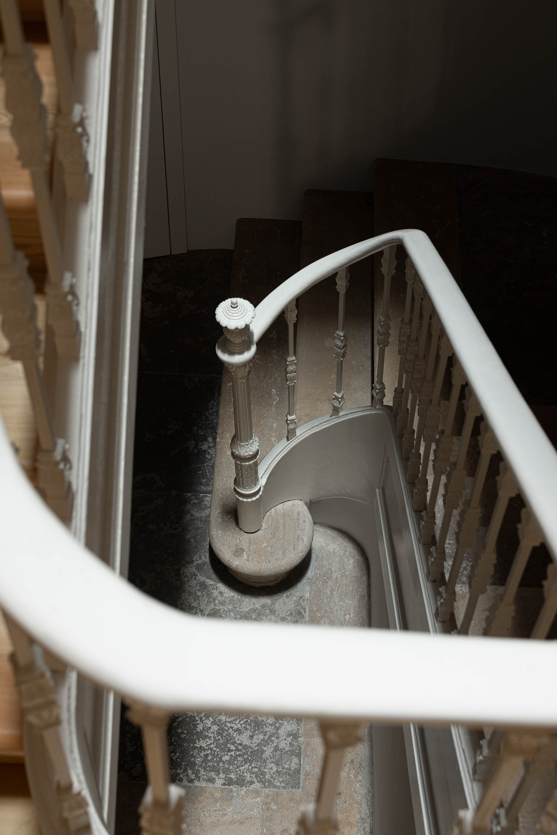 Escadaria: Vista de cima da escadaria com corrimão branco ornamentado e pavimento em pedra escura. — Victor Cordon arquitetura Fragmentos em Lisboa