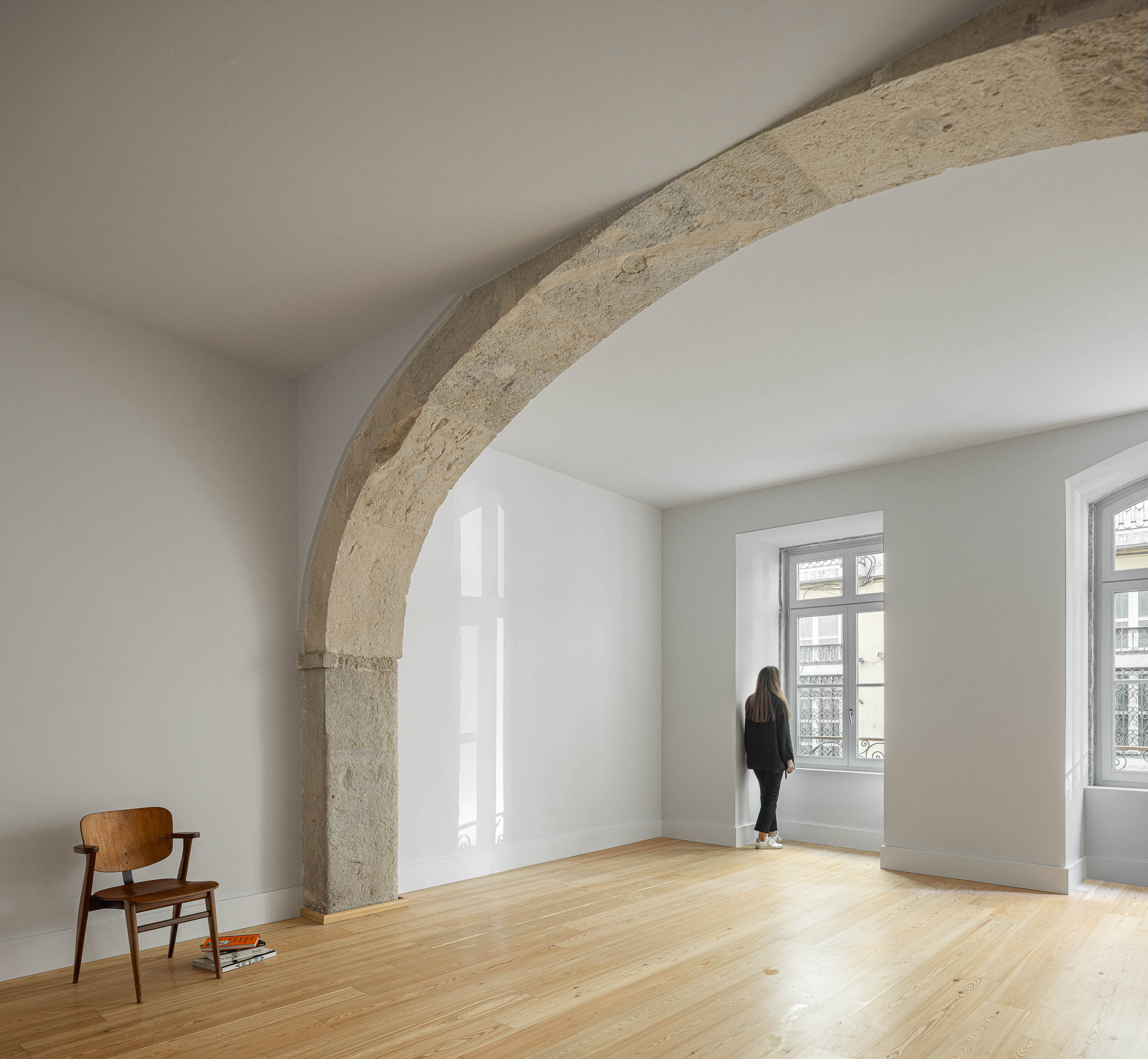 Sala de estar: Sala luminosa com arcos de pedra, pavimento em madeira clara e vista para a rua. — Victor Cordon arquitetura Fragmentos em Lisboa
