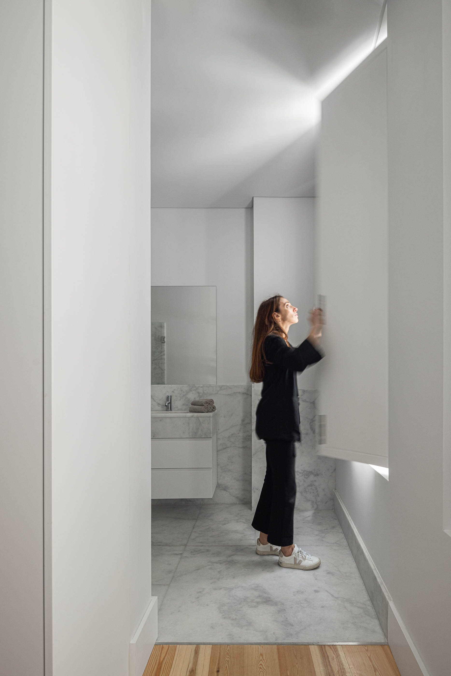 Casa de banho: Casa de banho minimalista com lavatório em mármore, espelho amplo e paredes brancas. — Victor Cordon arquitetura Fragmentos em Lisboa