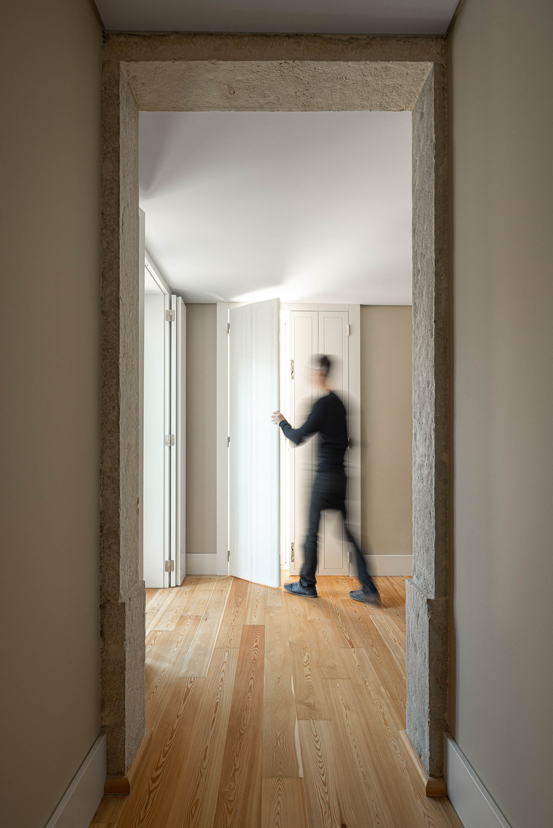 Corredor: Corredor com arcos de pedra, pavimento em madeira clara e paredes em tons neutros. — Victor Cordon arquitetura Fragmentos em Lisboa
