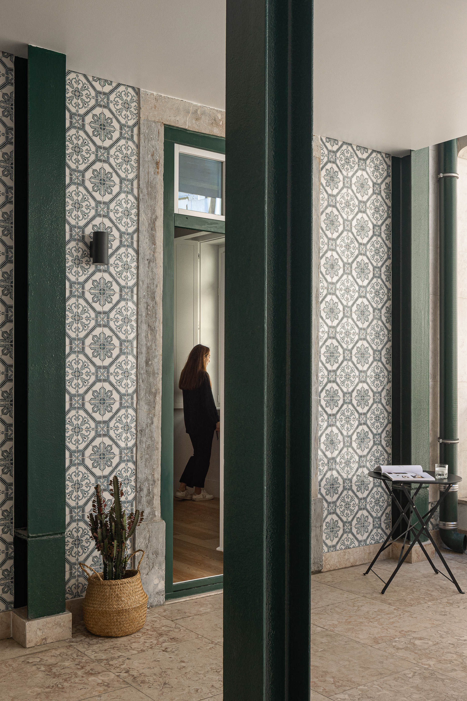 Varanda: Varanda com azulejos decorativos, pilar metálico verde e vista para o interior da casa. — Victor Cordon arquitetura Fragmentos em Lisboa