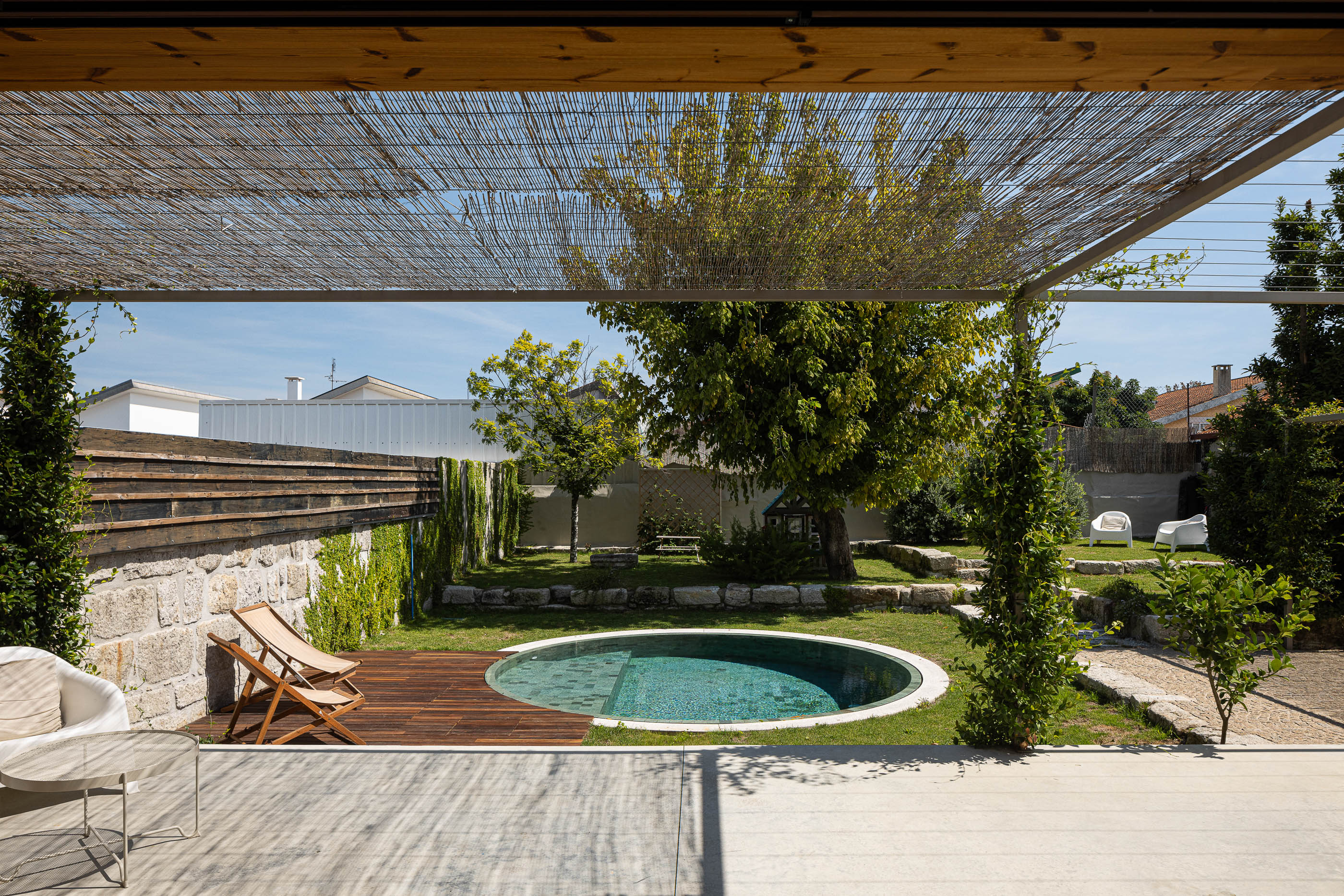 Piscina: Detalhe da piscina redonda com borda em pedra clara e relvado. — Casa Fonte Velha arquitetura Martins Pimenta – Arquitetura e Construção em Matosinhos