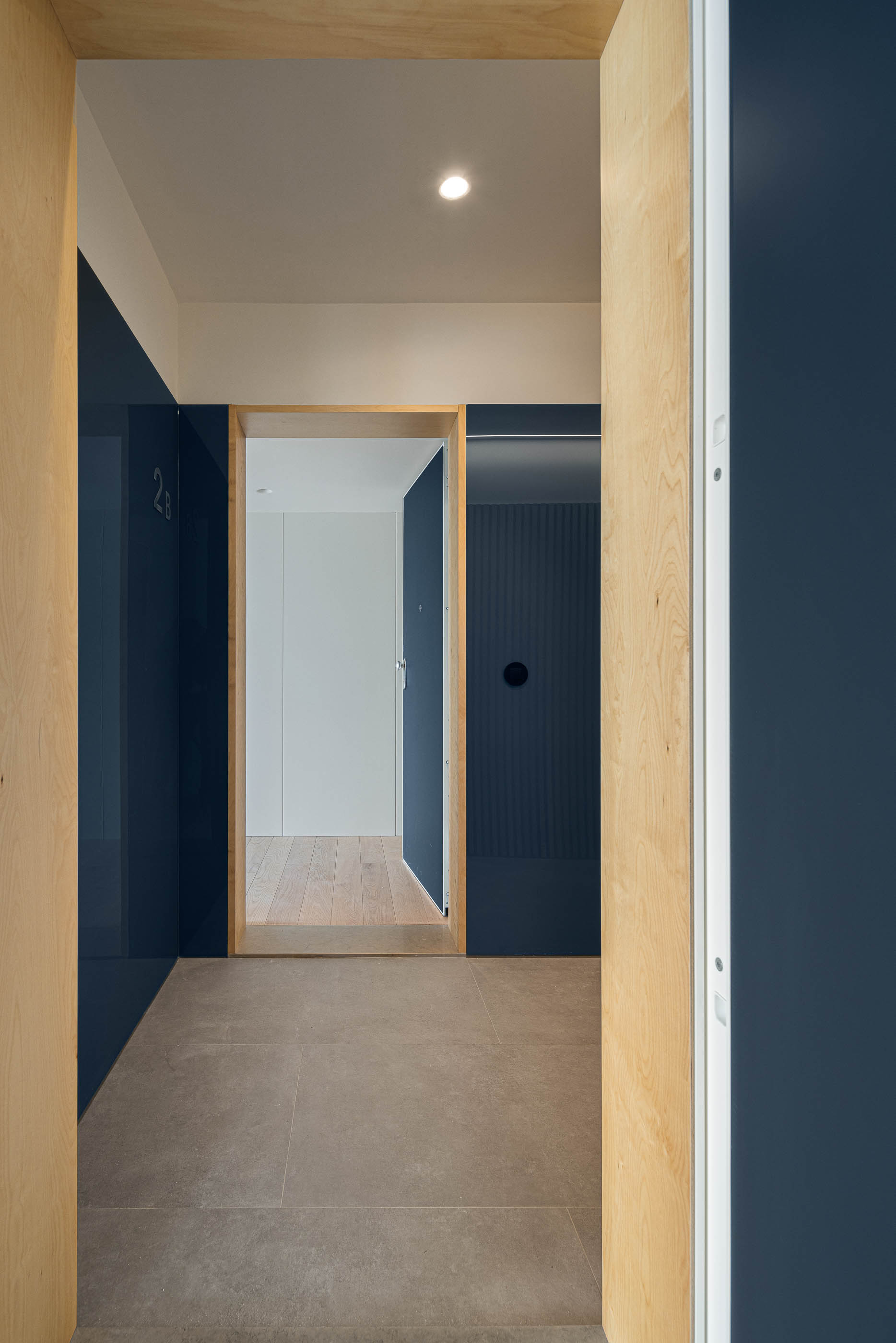 Hall de entrada: Corredor com paredes em azul escuro e madeira, pavimento cerâmico. — Edifício Seashore arquitetura Atelier d´Arquitectura Lopes da Costa em Vila Nova de Gaia