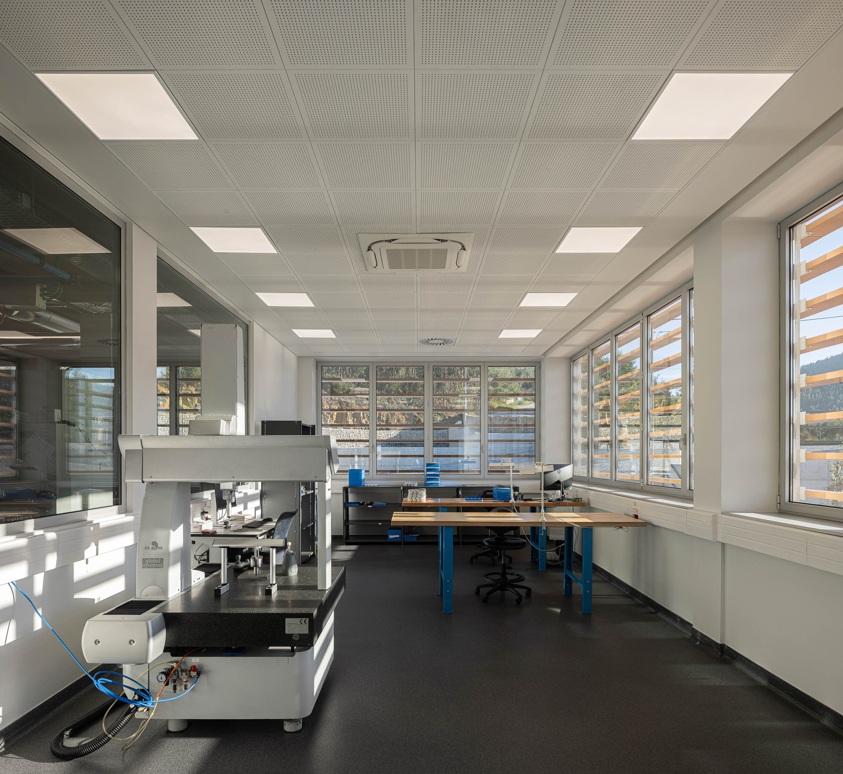 Laboratório: Sala com pavimento em borracha, paredes brancas, janelas amplas e equipamento de medição de precisão. — Unidade Industrial OROPOL arquitetura Em Paralelo em Castelo de Paiva