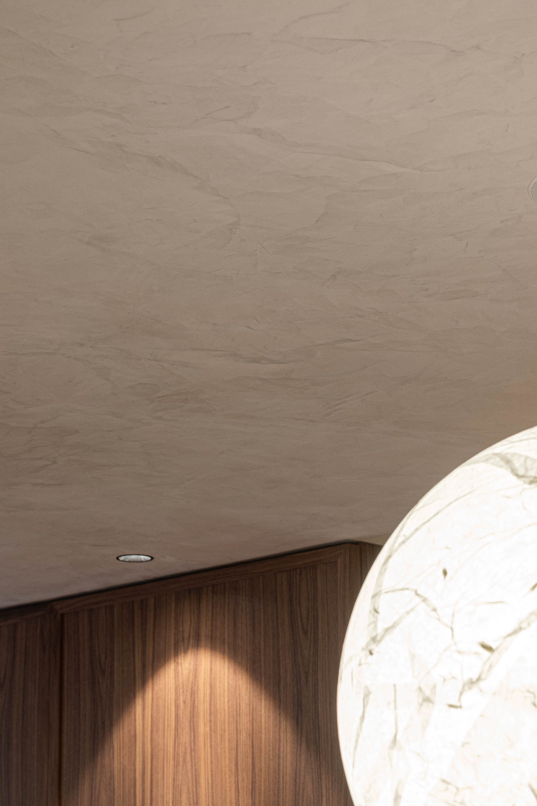 Teto: Textura irregular em tons neutros, com candeeiro embutido e parte de um candeeiro esférico. — Lugar Comum arquitetura edmundo* architecture + planning em vila do conde