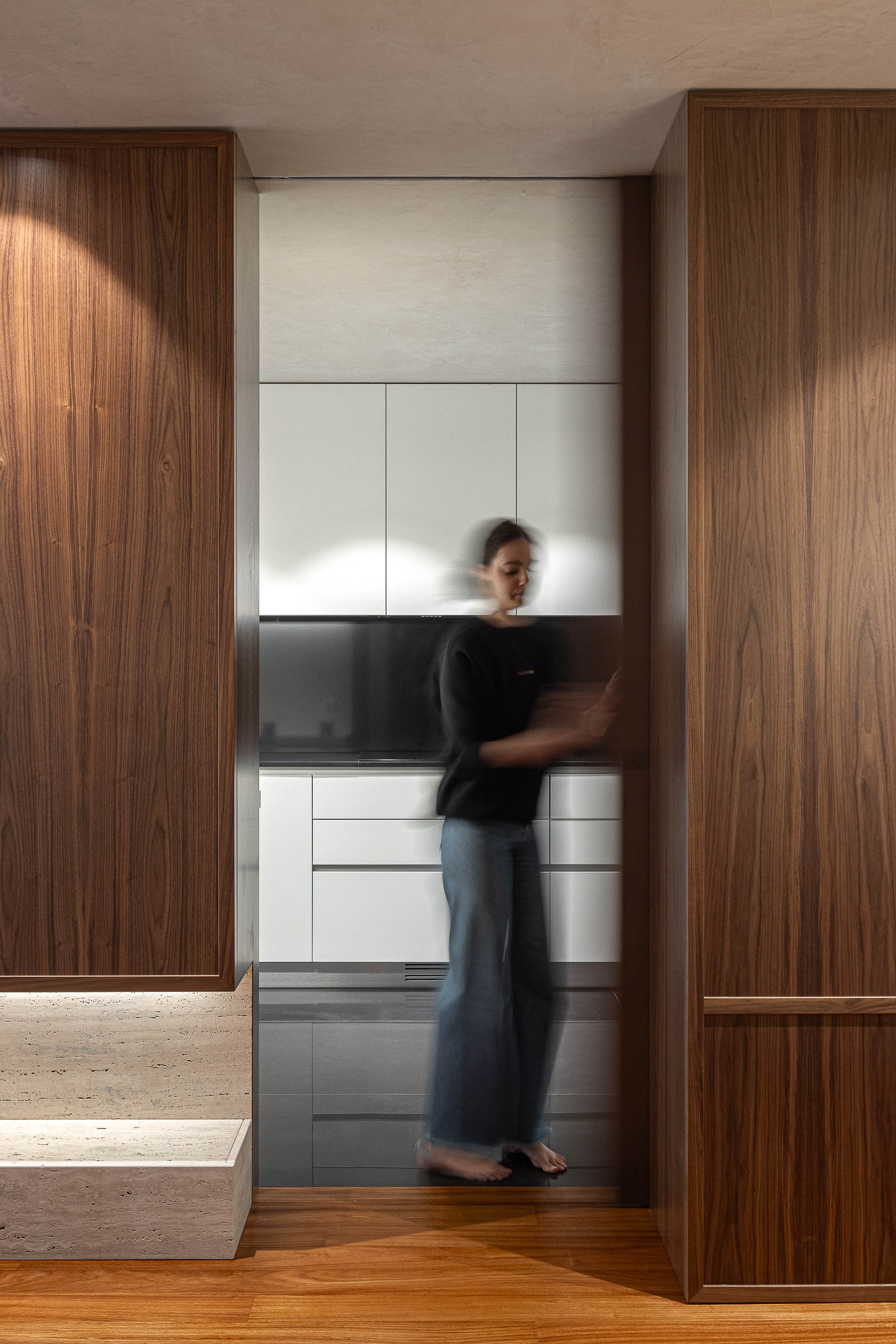Cozinha: Abertura para a cozinha com armários brancos e pavimento escuro. — Lugar Comum arquitetura edmundo* architecture + planning em vila do conde