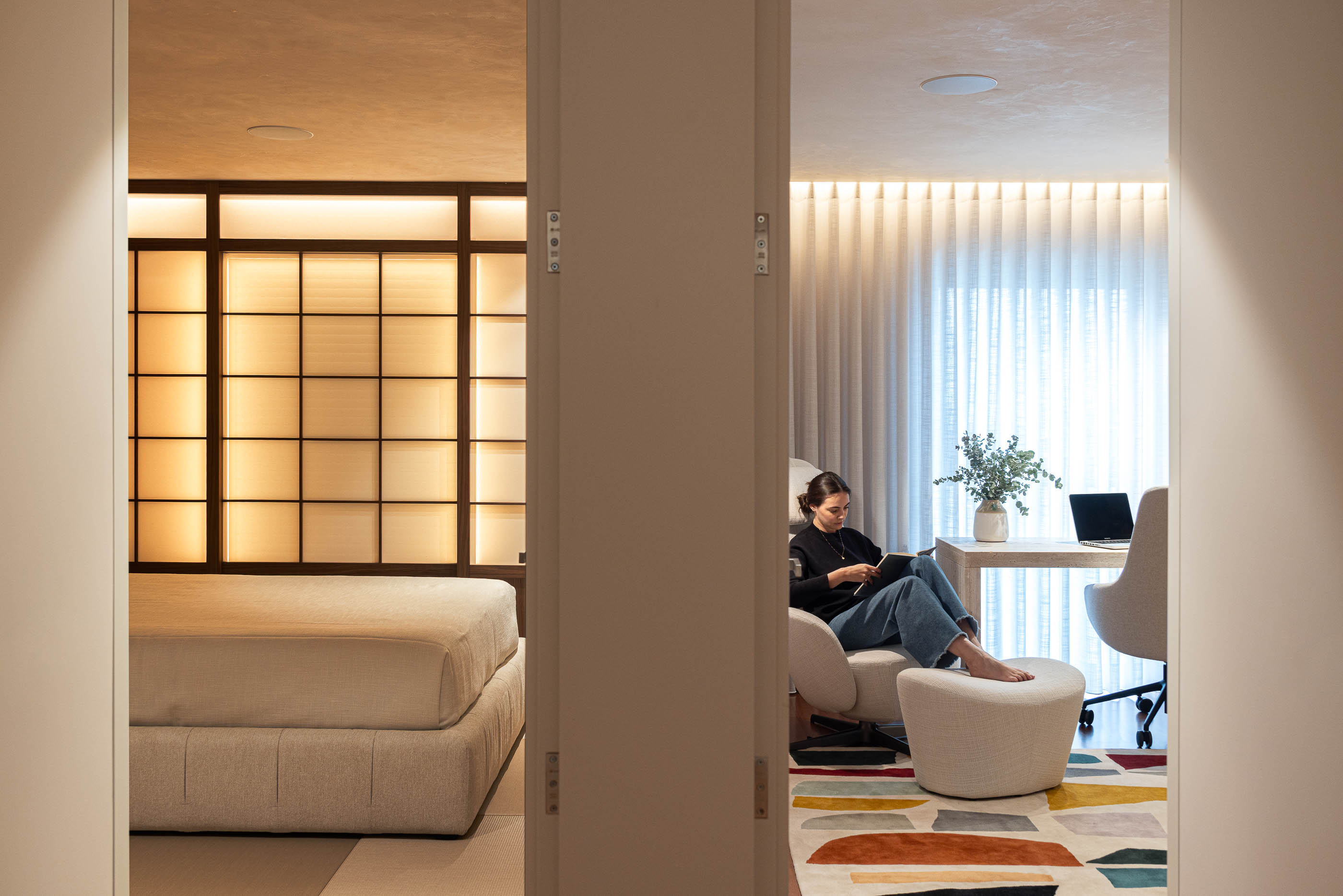 Escritório/Quarto: Vista do escritório para o quarto com cama baixa e painel retroiluminado. — Lugar Comum arquitetura edmundo* architecture + planning em vila do conde