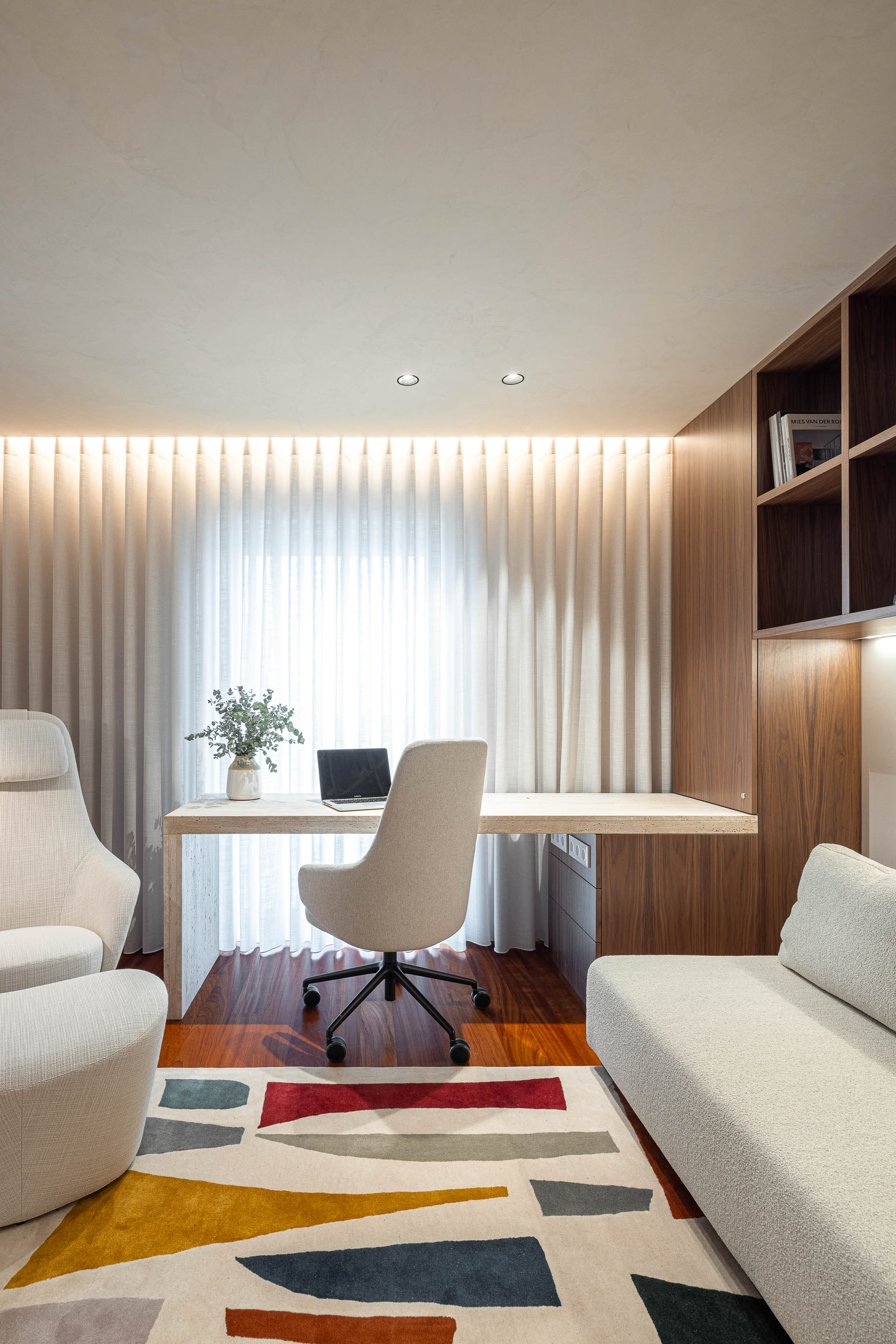 Escritório: Secretária em madeira clara, cadeira de escritório e sofá bege sobre alcatifa colorida. — Lugar Comum arquitetura edmundo* architecture + planning em vila do conde