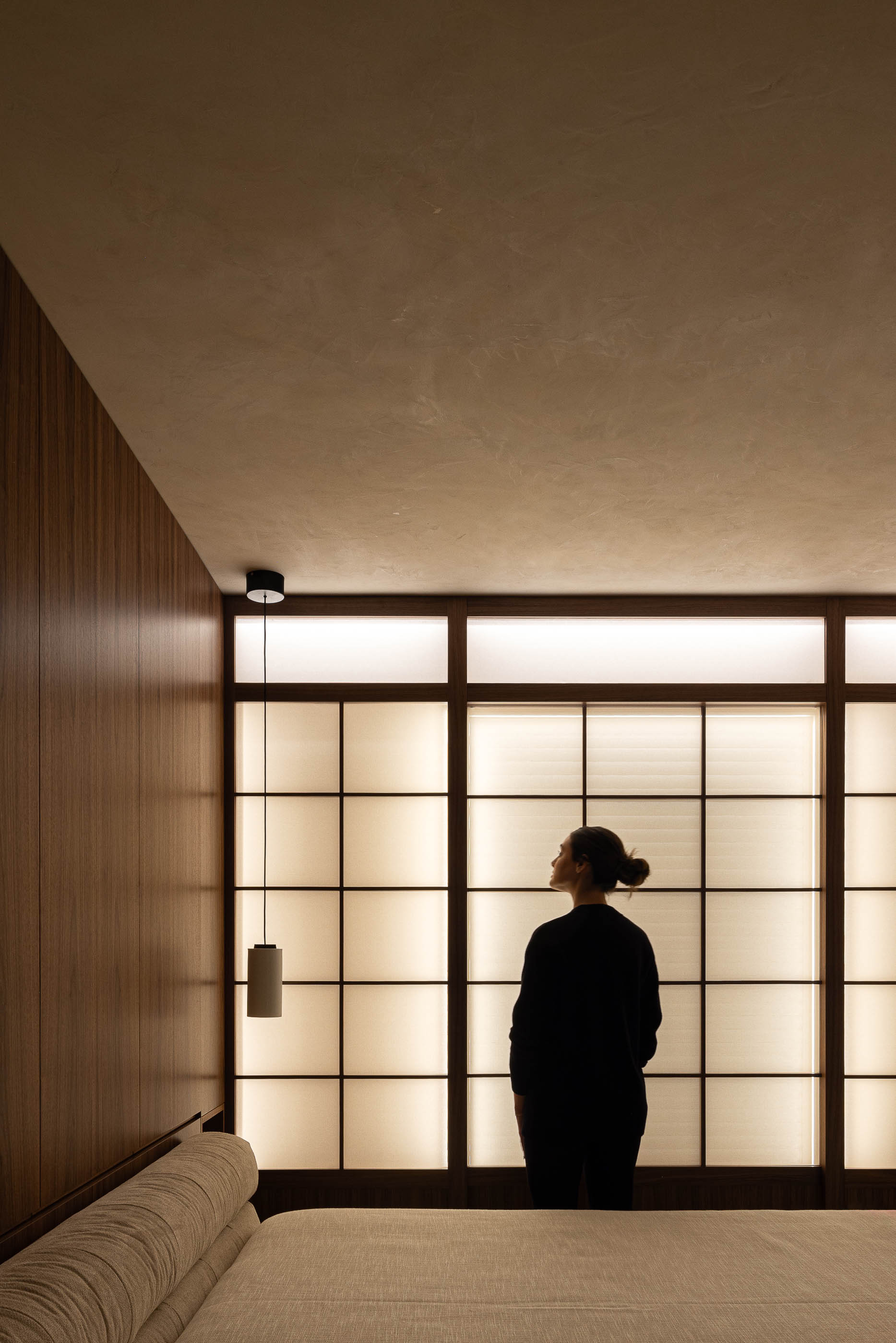 Quarto: Painel japonês retroiluminado, candeeiro suspenso e cama baixa. — Lugar Comum arquitetura edmundo* architecture + planning em vila do conde