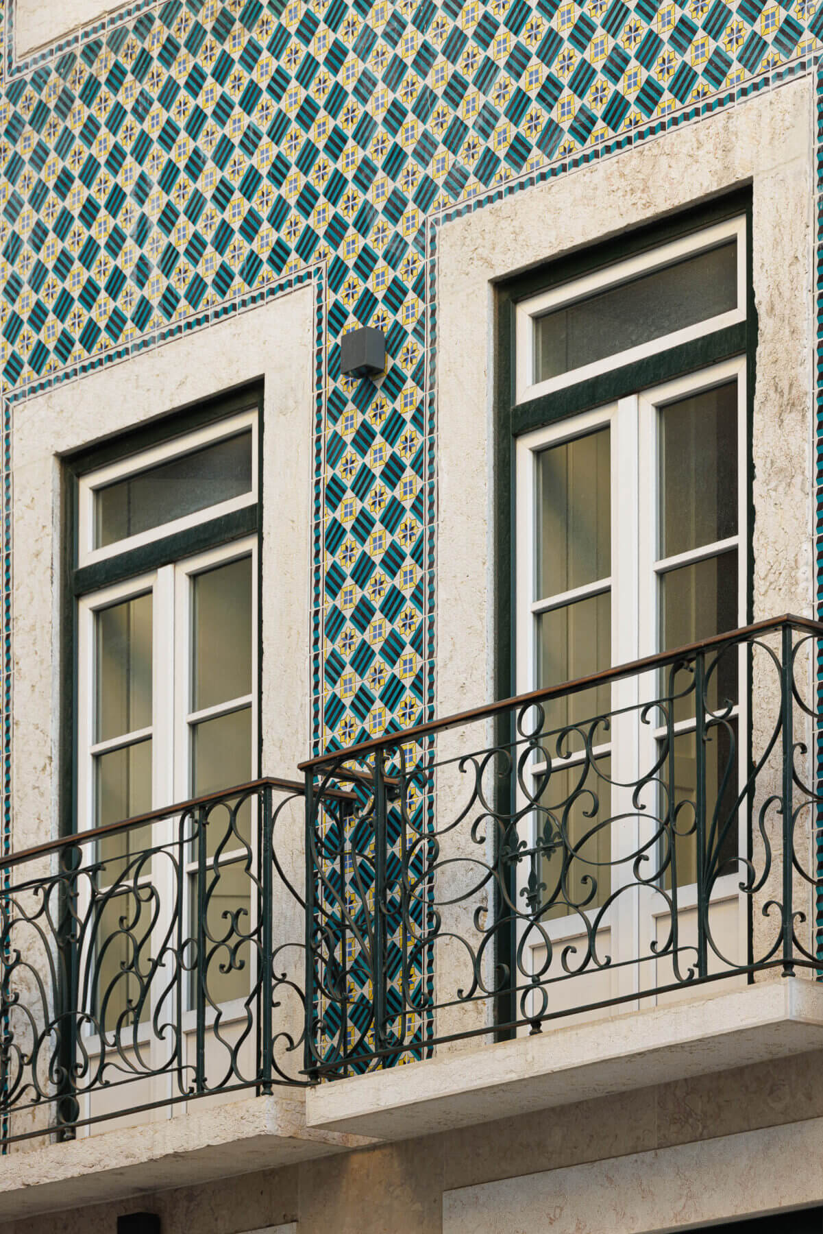 Varanda: Fachada com azulejos decorativos, janelas brancas e varanda em ferro trabalhado. — Villa Chiado arquitetura Pedro Carrilho Arquitectos em Lisboa