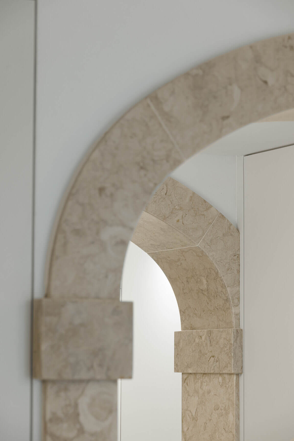 Corredor: Detalhe de arco em pedra com porta branca ao fundo, corredor minimalista. — Villa Chiado arquitetura Pedro Carrilho Arquitectos em Lisboa