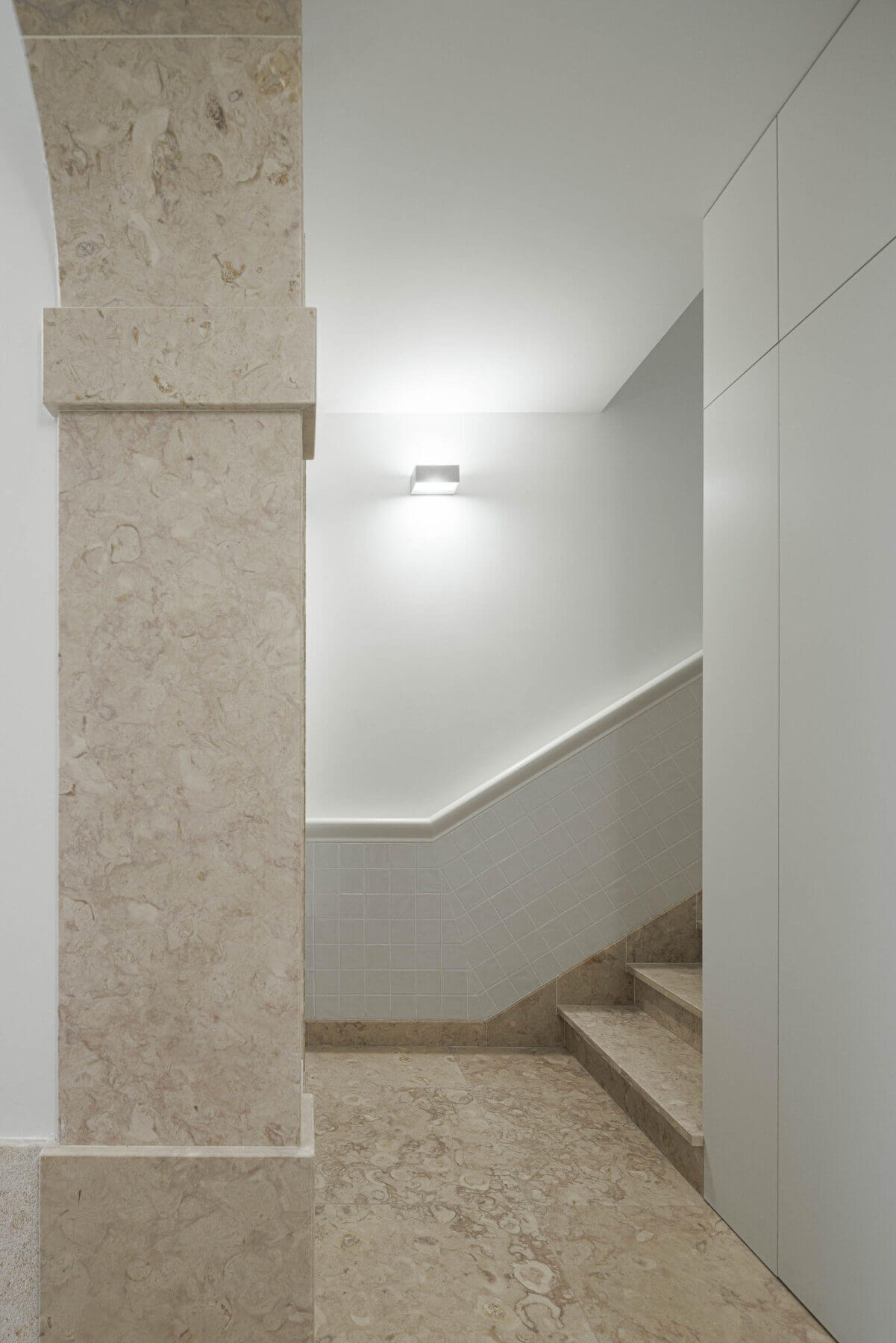 Escadas: Escadas com degraus em pedra, paredes brancas com azulejos e iluminação discreta. — Villa Chiado arquitetura Pedro Carrilho Arquitectos em Lisboa