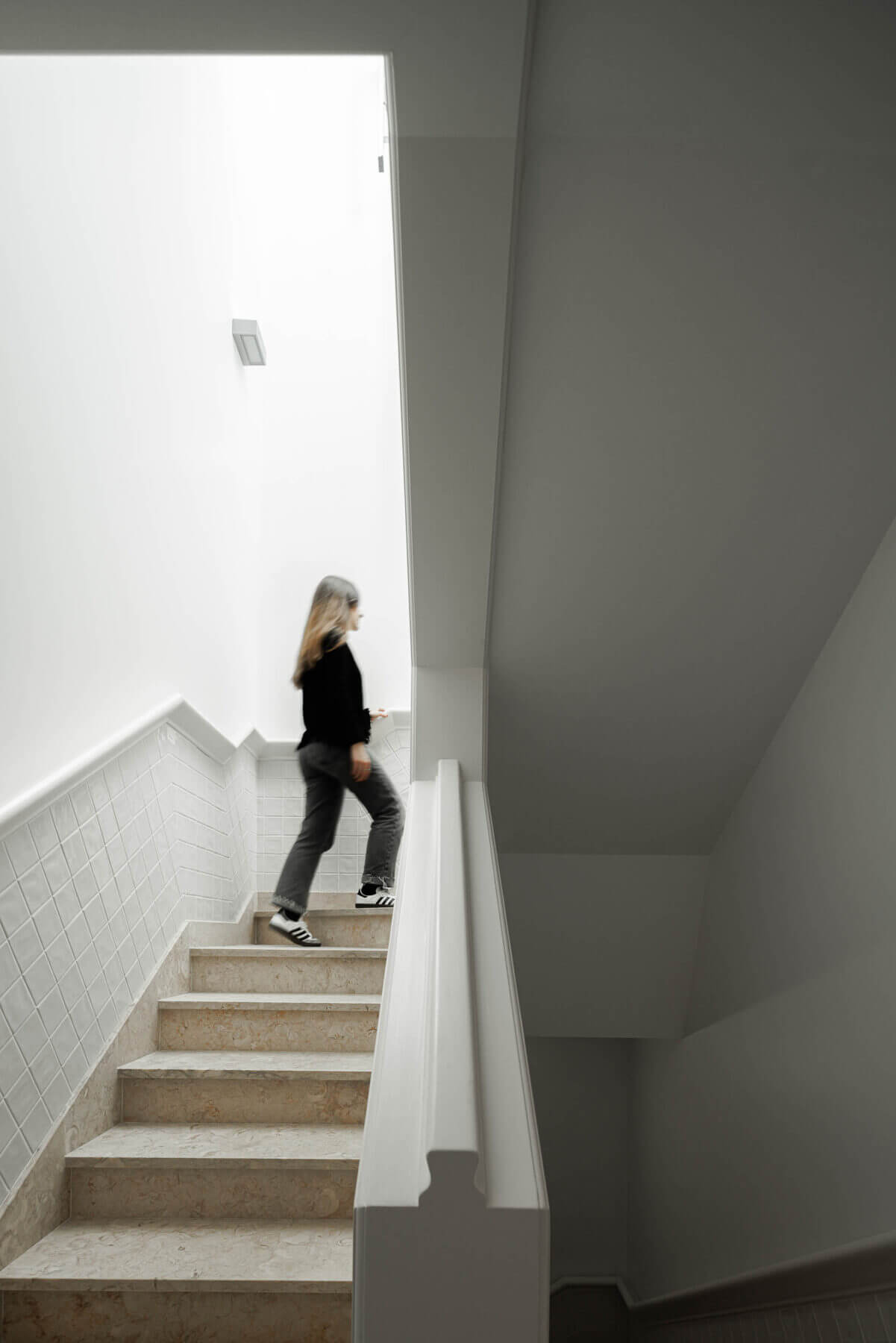 Escadas: Escadas com degraus em pedra, azulejos brancos e luz natural vinda do topo. — Villa Chiado arquitetura Pedro Carrilho Arquitectos em Lisboa