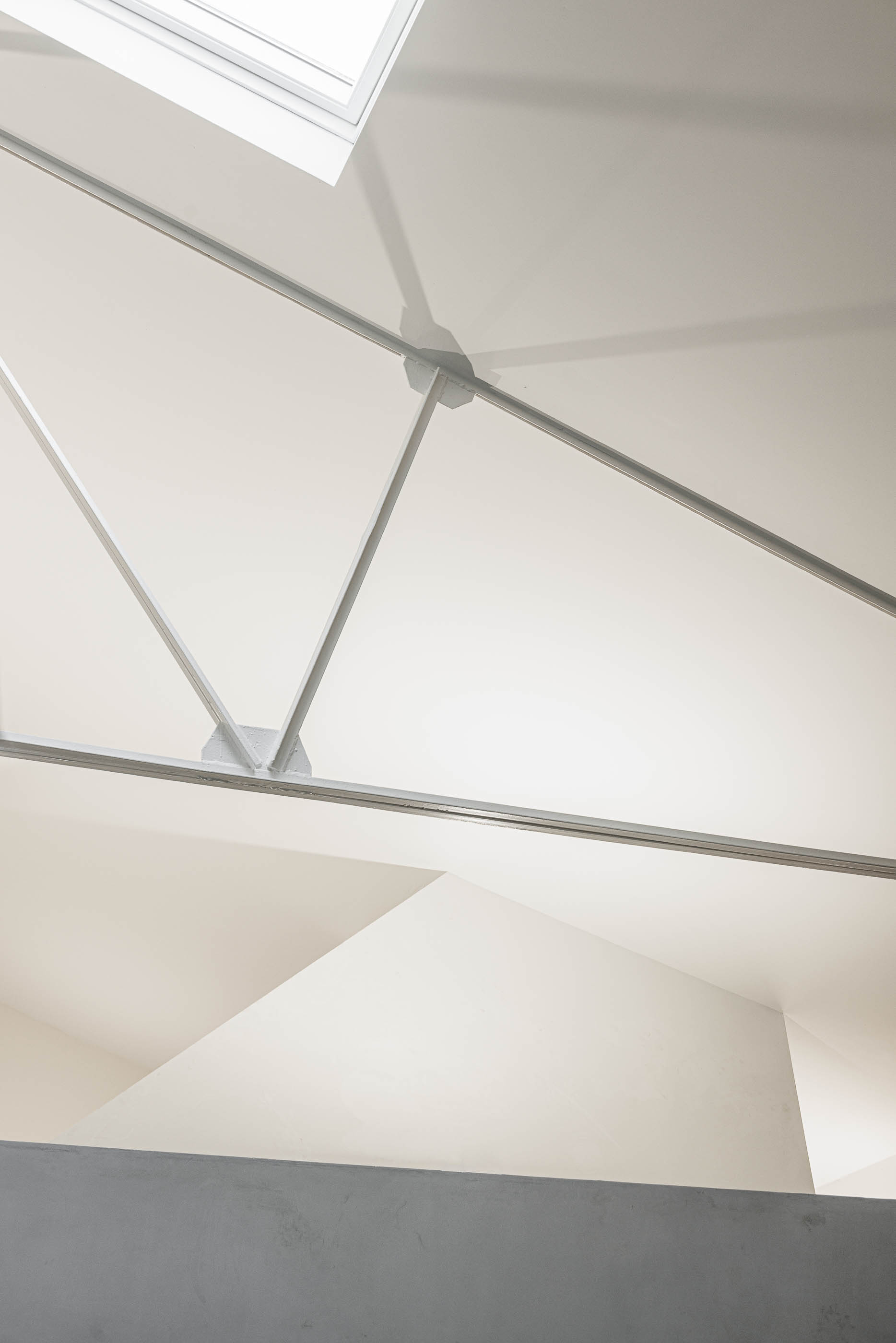 Refeitório: Detalhe da estrutura metálica branca do telhado e claraboia, com parede em cimento afagado. — Indústria | A10 arquitetura BOX arquitectos em São Miguel