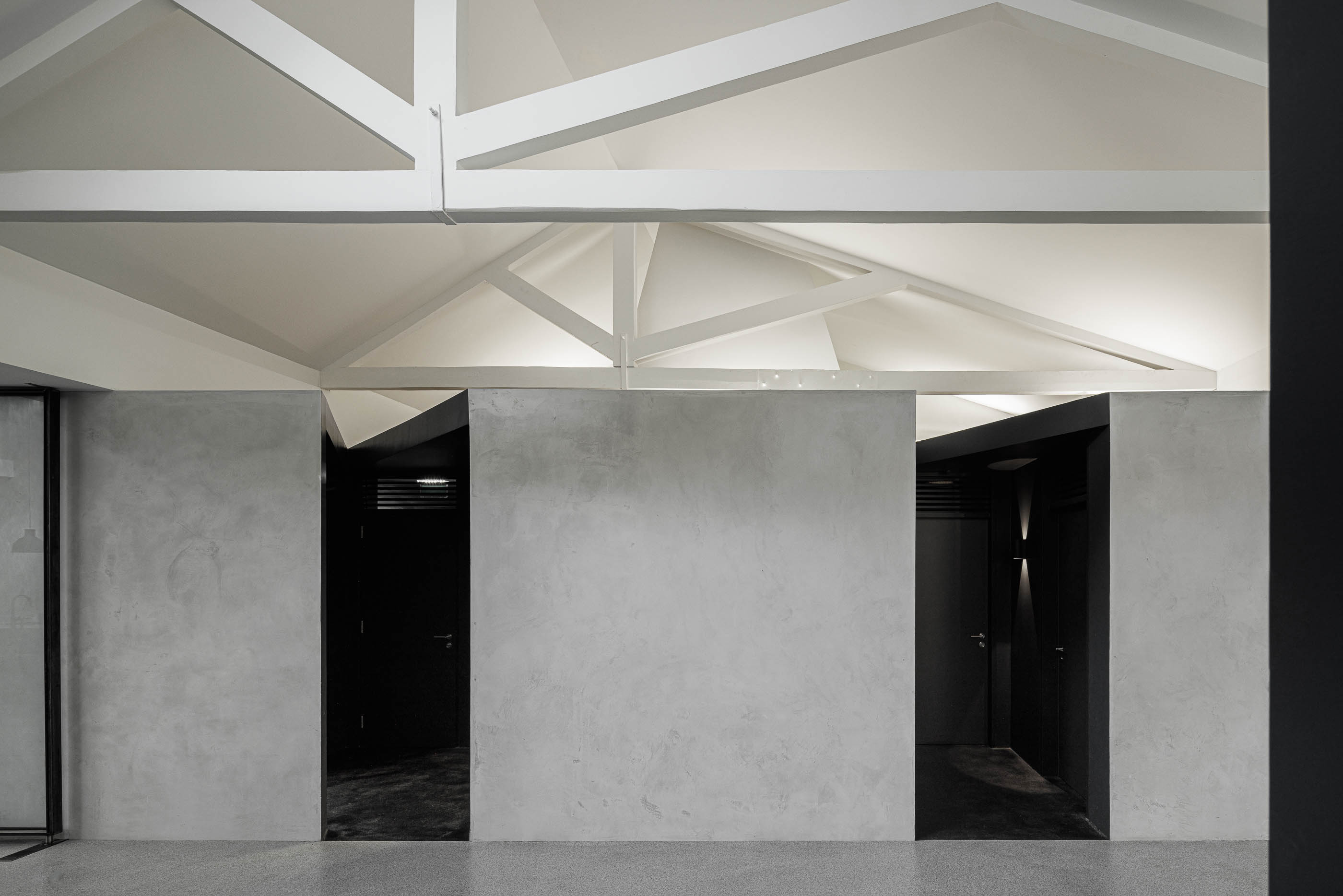 Corredor: Paredes em cimento afagado, estrutura branca no teto e portas pretas, com pavimento cinzento. — Indústria | A10 arquitetura BOX arquitectos em São Miguel
