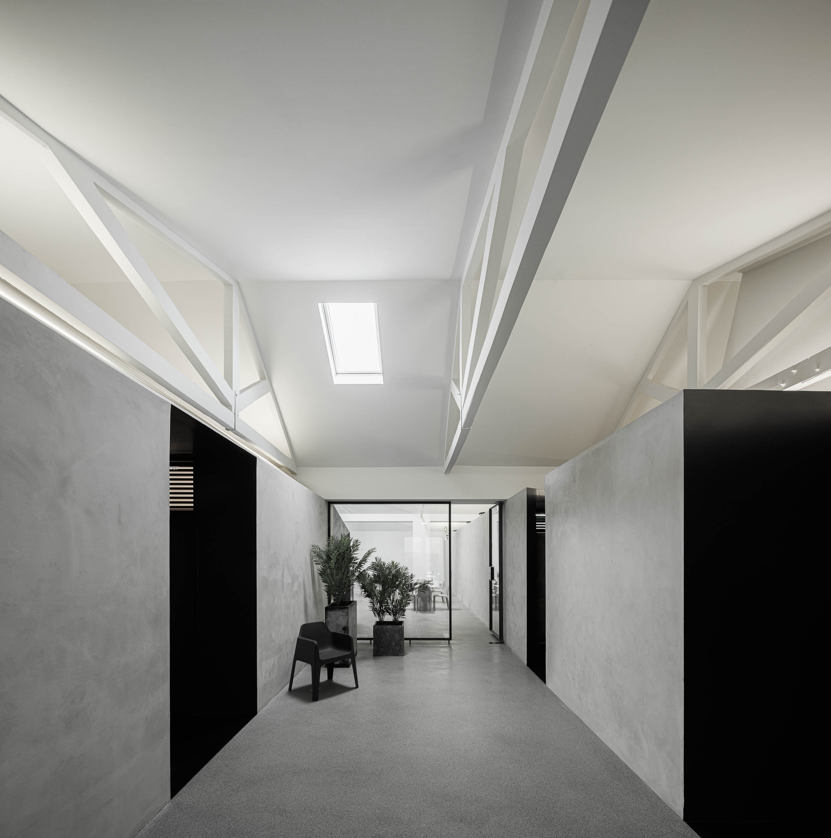 Corredor: Longo corredor com paredes em cimento afagado, portas pretas e estrutura branca no teto, pavimento cinzento. — Indústria | A10 arquitetura BOX arquitectos em São Miguel