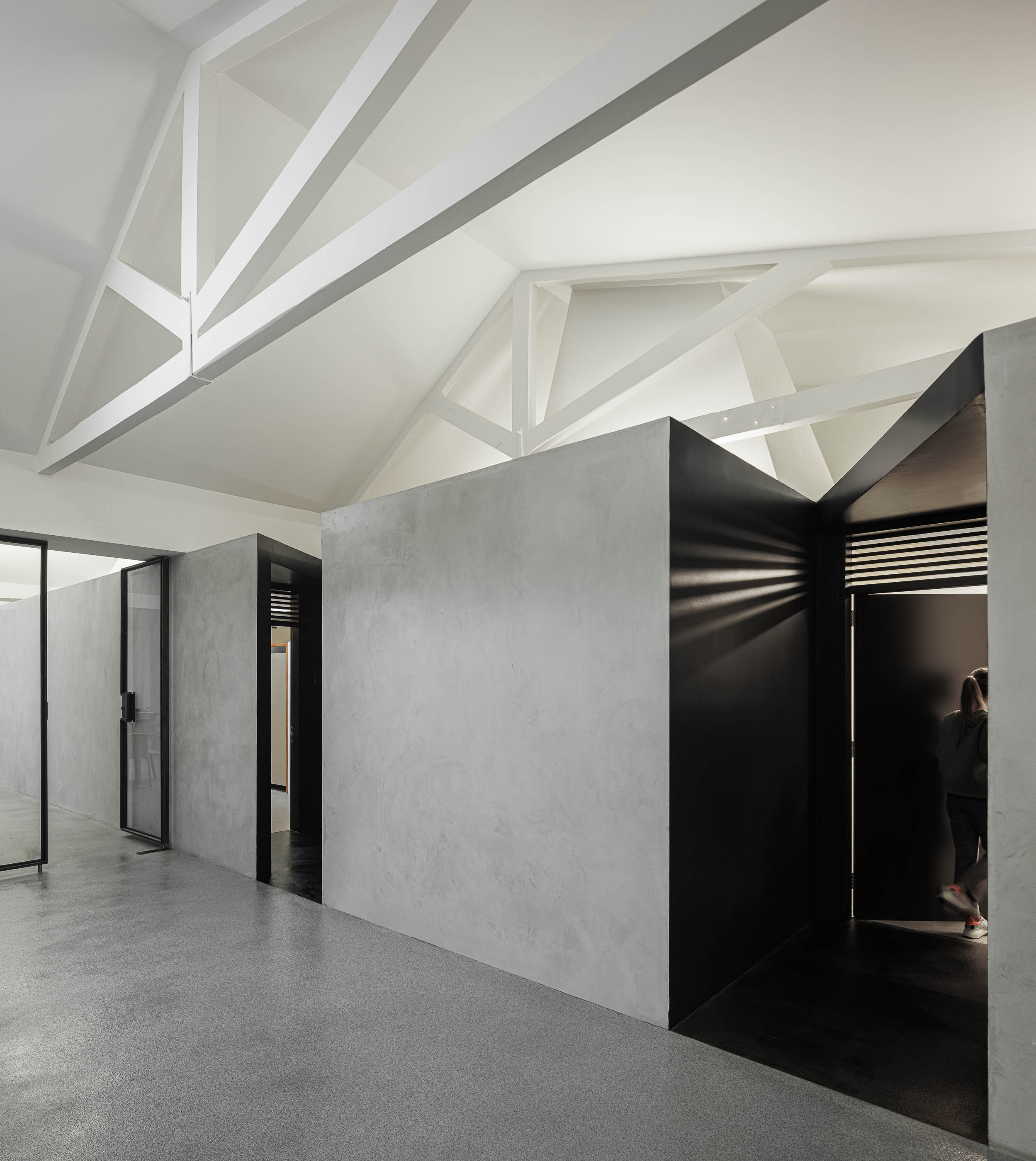 Corredor: Perspectiva do corredor com paredes em cimento afagado, portas pretas e estrutura branca no teto. — Indústria | A10 arquitetura BOX arquitectos em São Miguel