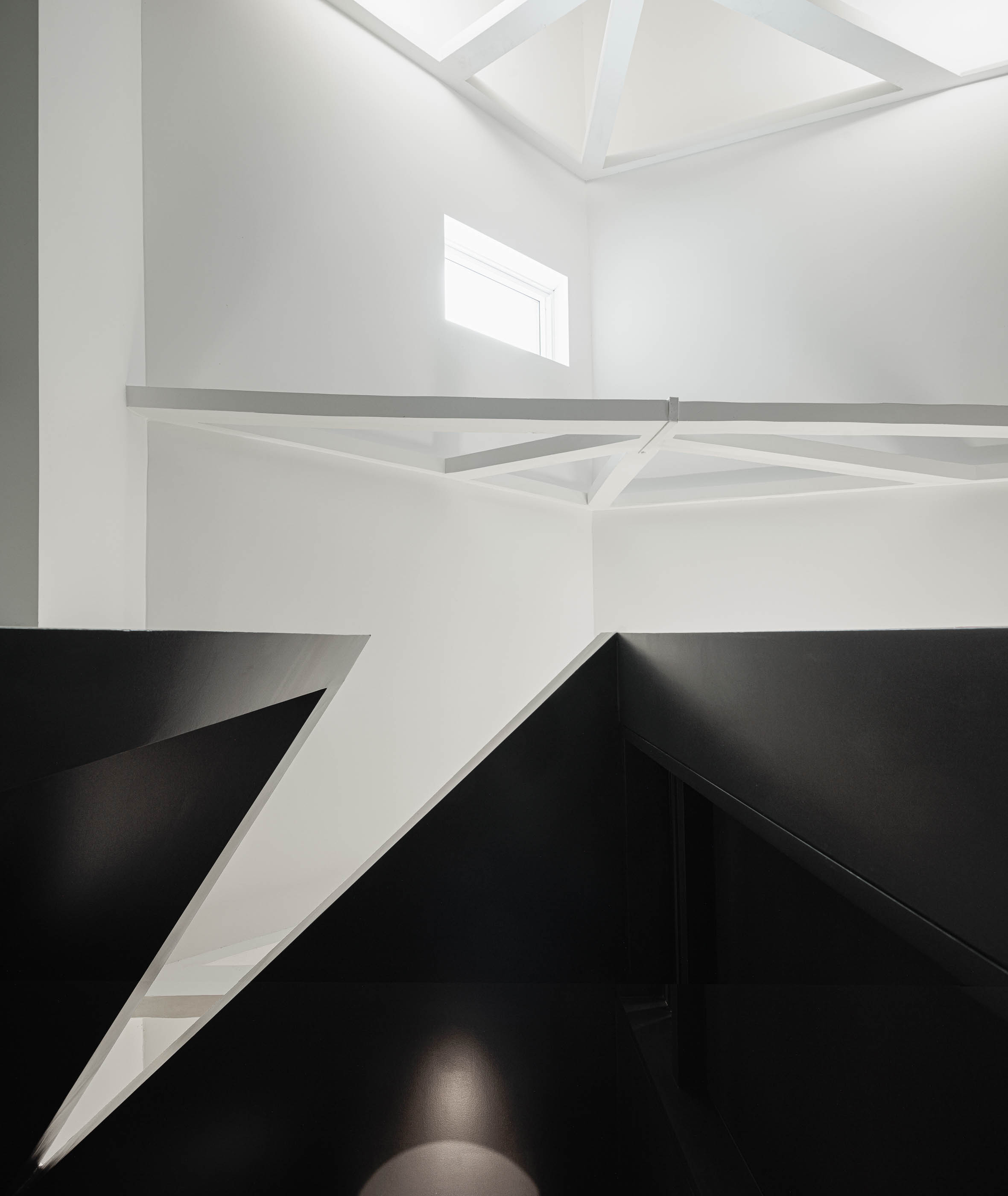 Teto: Detalhe da estrutura branca em madeira do telhado e parede preta geométrica. — Indústria | A10 arquitetura BOX arquitectos em São Miguel
