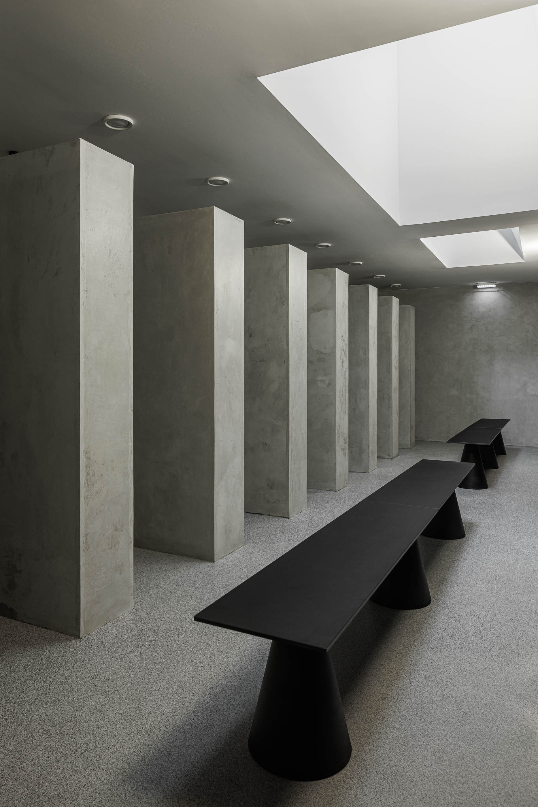 Balneário: Detalhe do banco preto e cacifos pretos com espelho, pavimento cinzento. — Indústria | A10 arquitetura BOX arquitectos em São Miguel