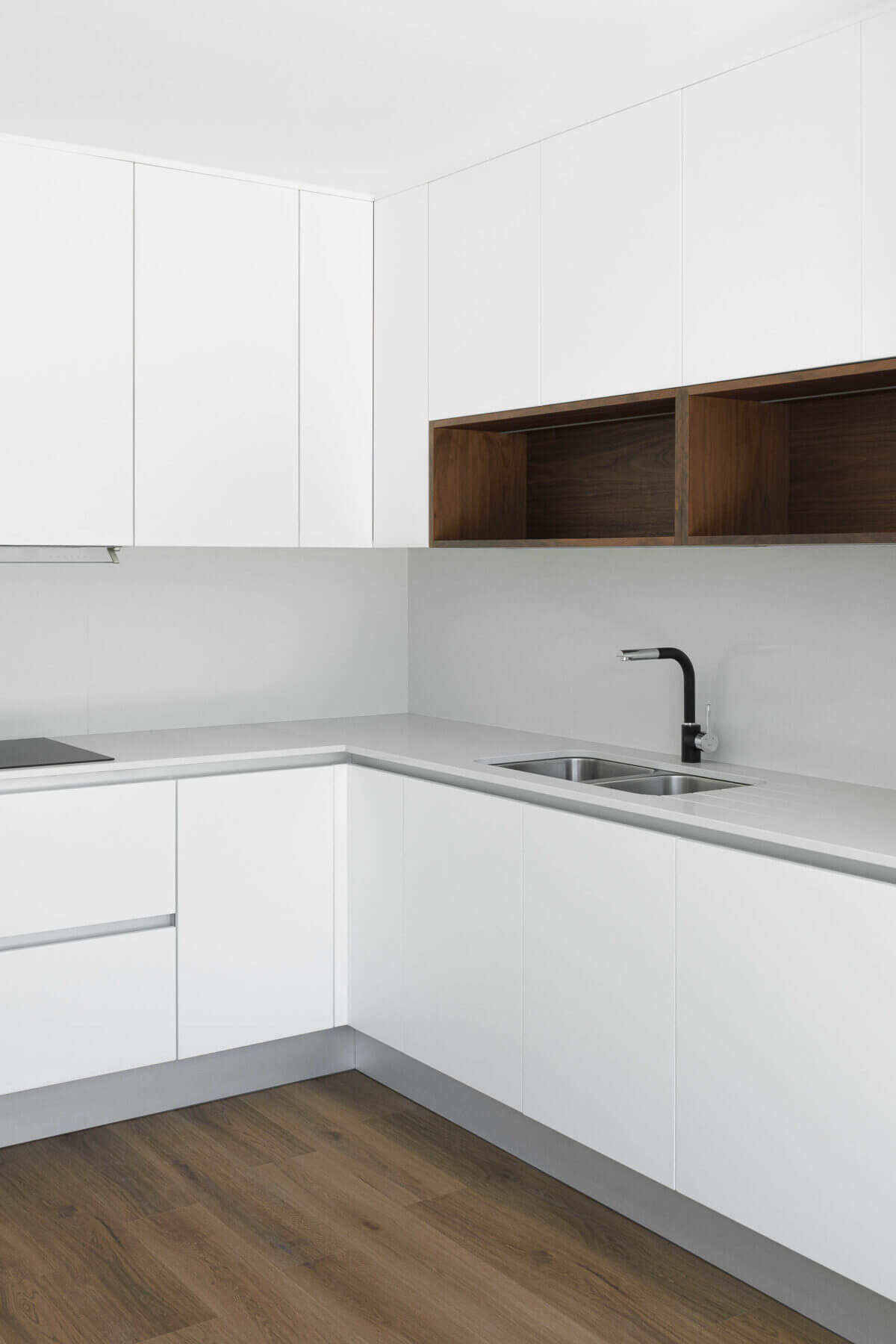Cozinha: Detalhe da bancada em branco com lava-loiça em inox e armários brancos com nichos em madeira. — Casas BD arquitetura Esquissos Arquitectura em Sintra