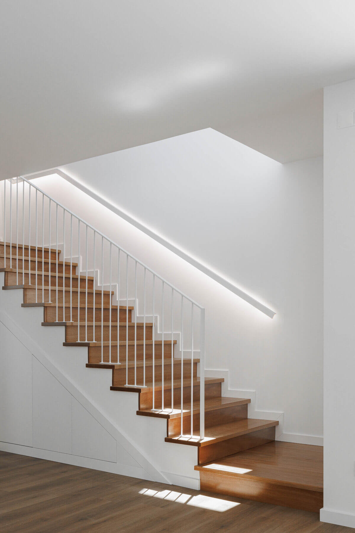 Escadas: Escadas em madeira com guarda-corpo branco, iluminação embutida e armários embutidos. — Casas BD arquitetura Esquissos Arquitectura em Sintra