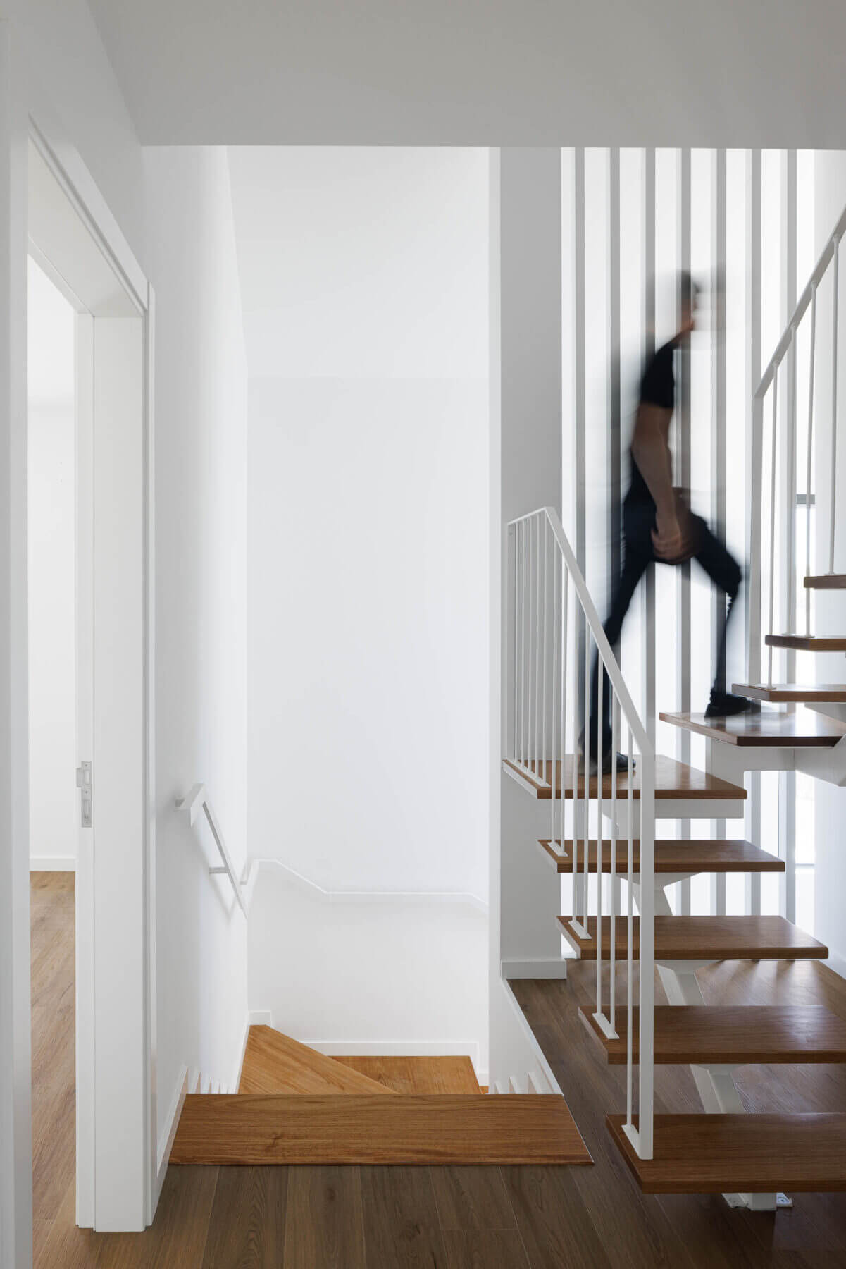Escadas: Pessoa a subir escadas de madeira com estrutura e guarda-corpo brancos. — Casas BD arquitetura Esquissos Arquitectura em Sintra