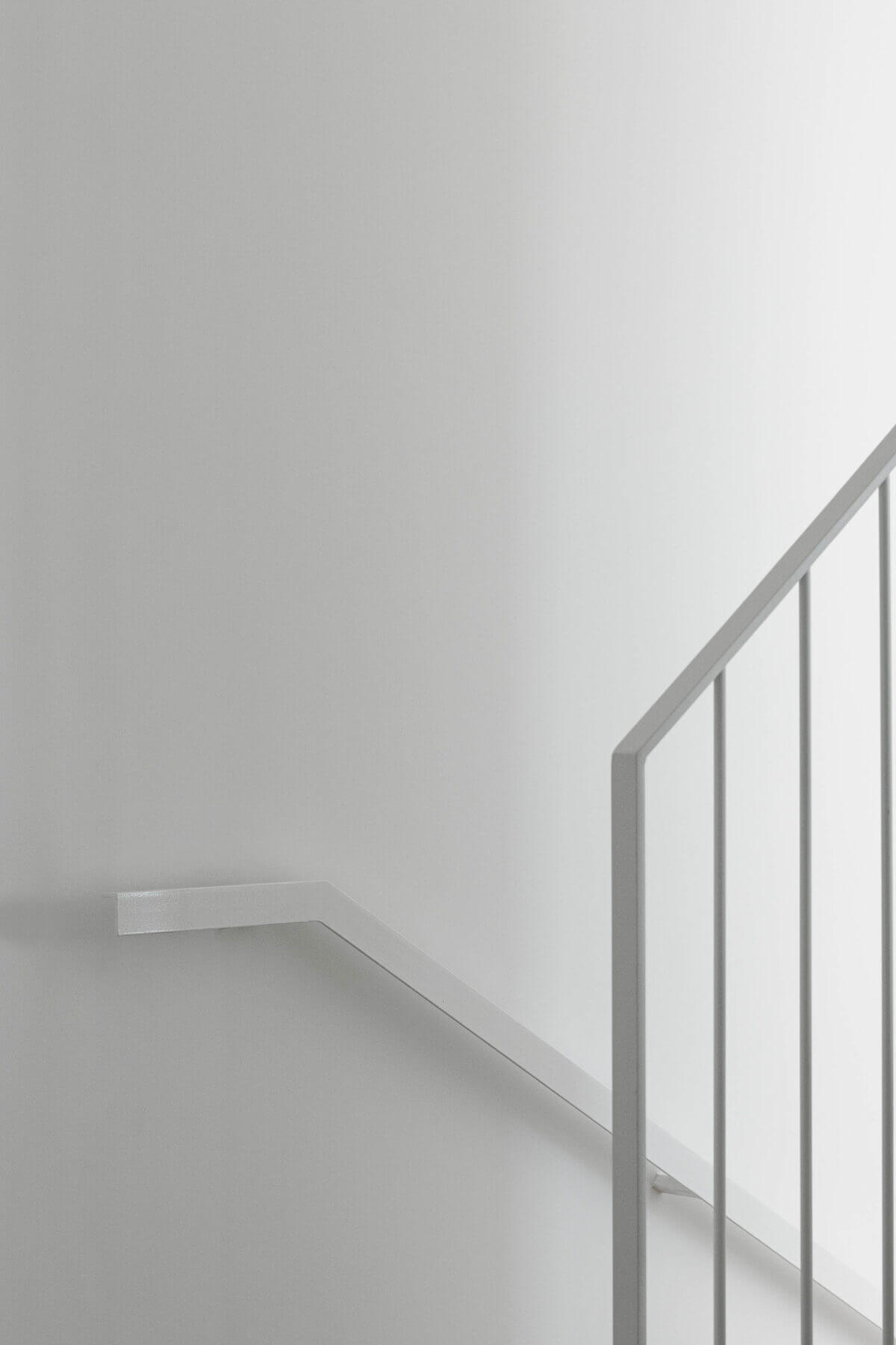 Escadas: Detalhe do corrimão branco das escadas contra uma parede branca. — Casas BD arquitetura Esquissos Arquitectura em Sintra