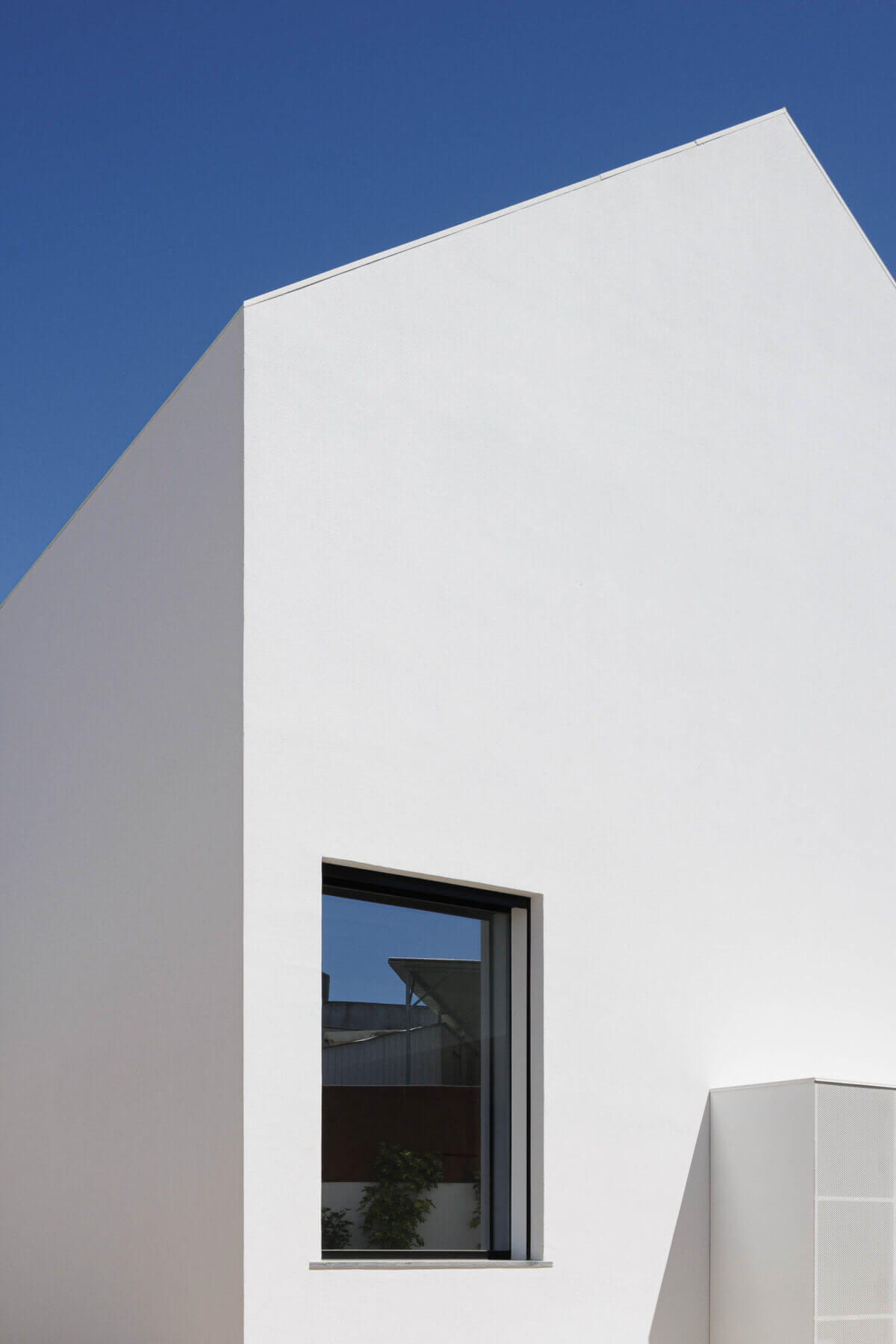 Fachada: Moradia branca com janela preta e detalhe da ventilação exterior. — Casas BD arquitetura Esquissos Arquitectura em Sintra