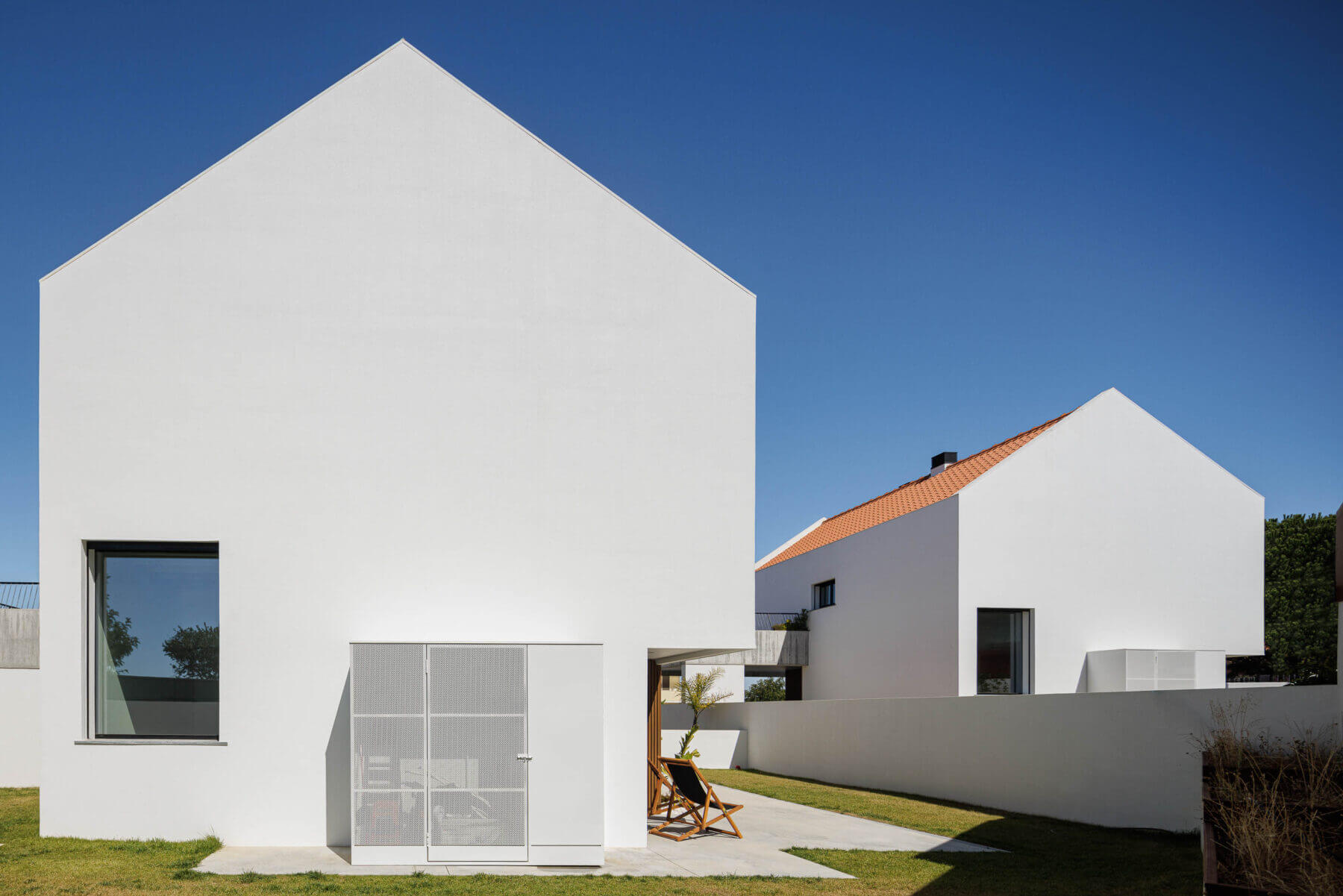Fachada: Vista das duas moradias brancas com telhado cerâmico e varanda em betão aparente. — Casas BD arquitetura Esquissos Arquitectura em Sintra