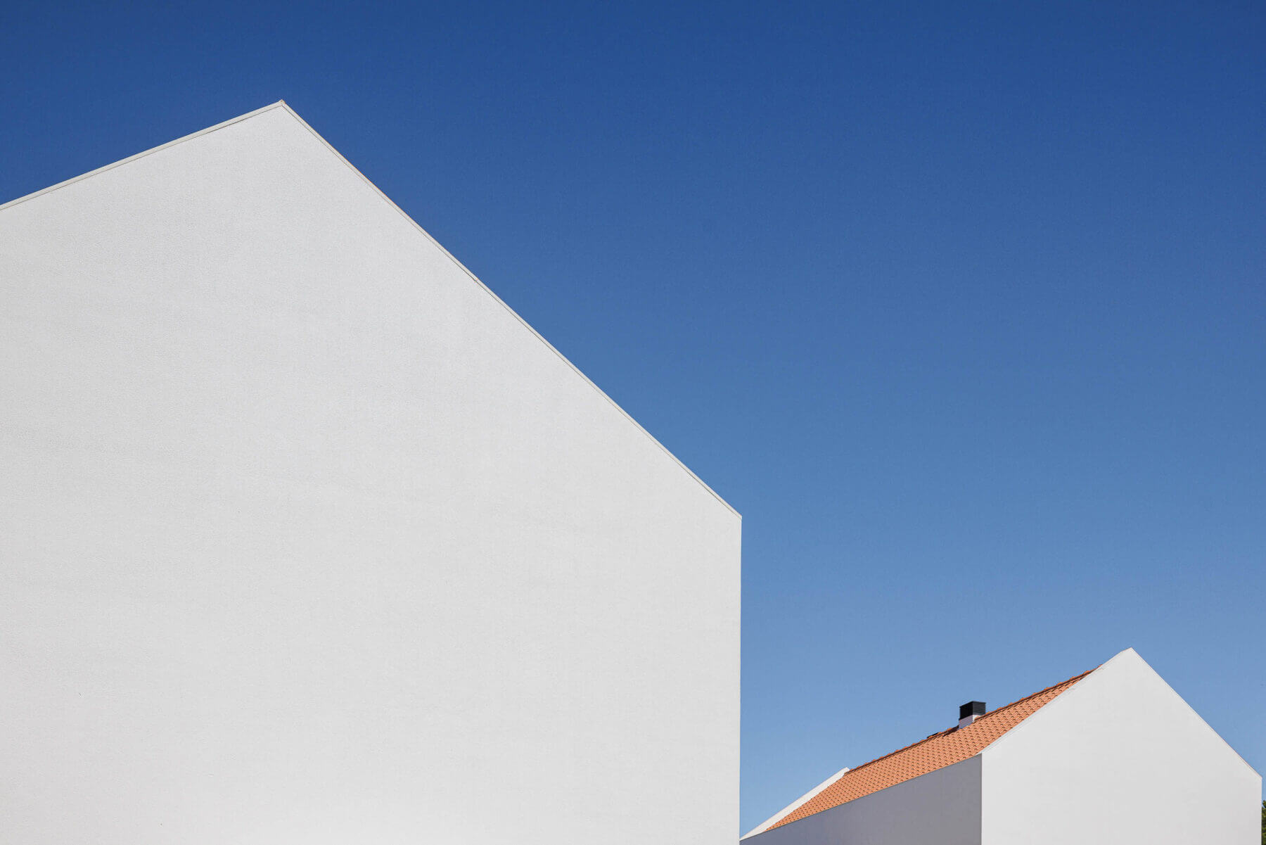 Fachada: Detalhe da moradia branca com telhado cerâmico e varanda em betão aparente com vegetação. — Casas BD arquitetura Esquissos Arquitectura em Sintra