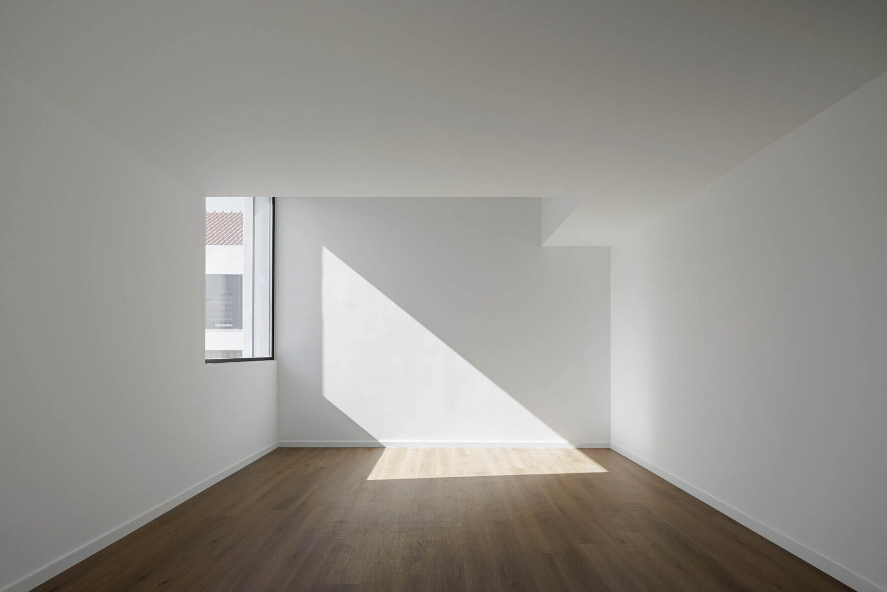 Quarto: Quarto vazio com pavimento em madeira e janela com vista para a moradia vizinha. — Casas BD arquitetura Esquissos Arquitectura em Sintra