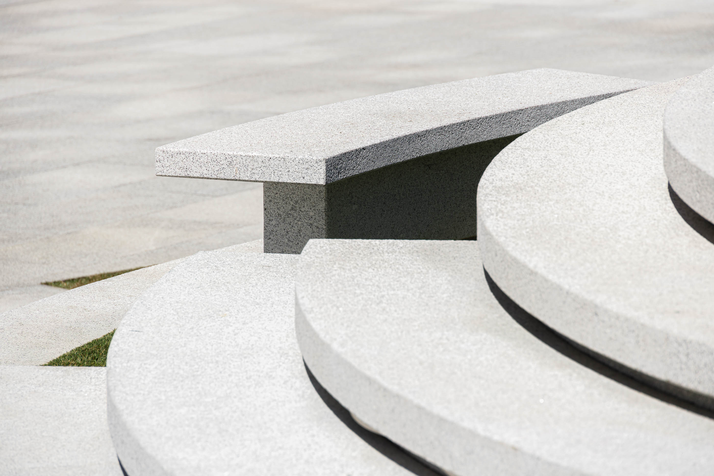 Praça: Detalhe da escadaria semicircular em granito cinza claro com banco integrado. — Requalificação da Praça do Município de Ribeira de Pena arquitetura AXR - Arquitetura e Design em Vila Real